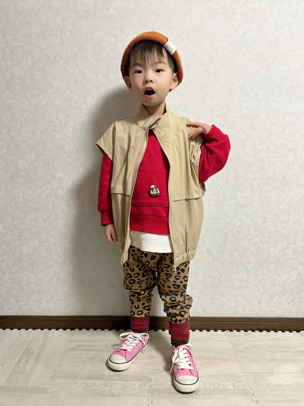 ベージュ系のベスト、レッド系のスウェット、ブラウン系のスウェットパンツを着用したキッズの冬コーディネートの1枚目の写真