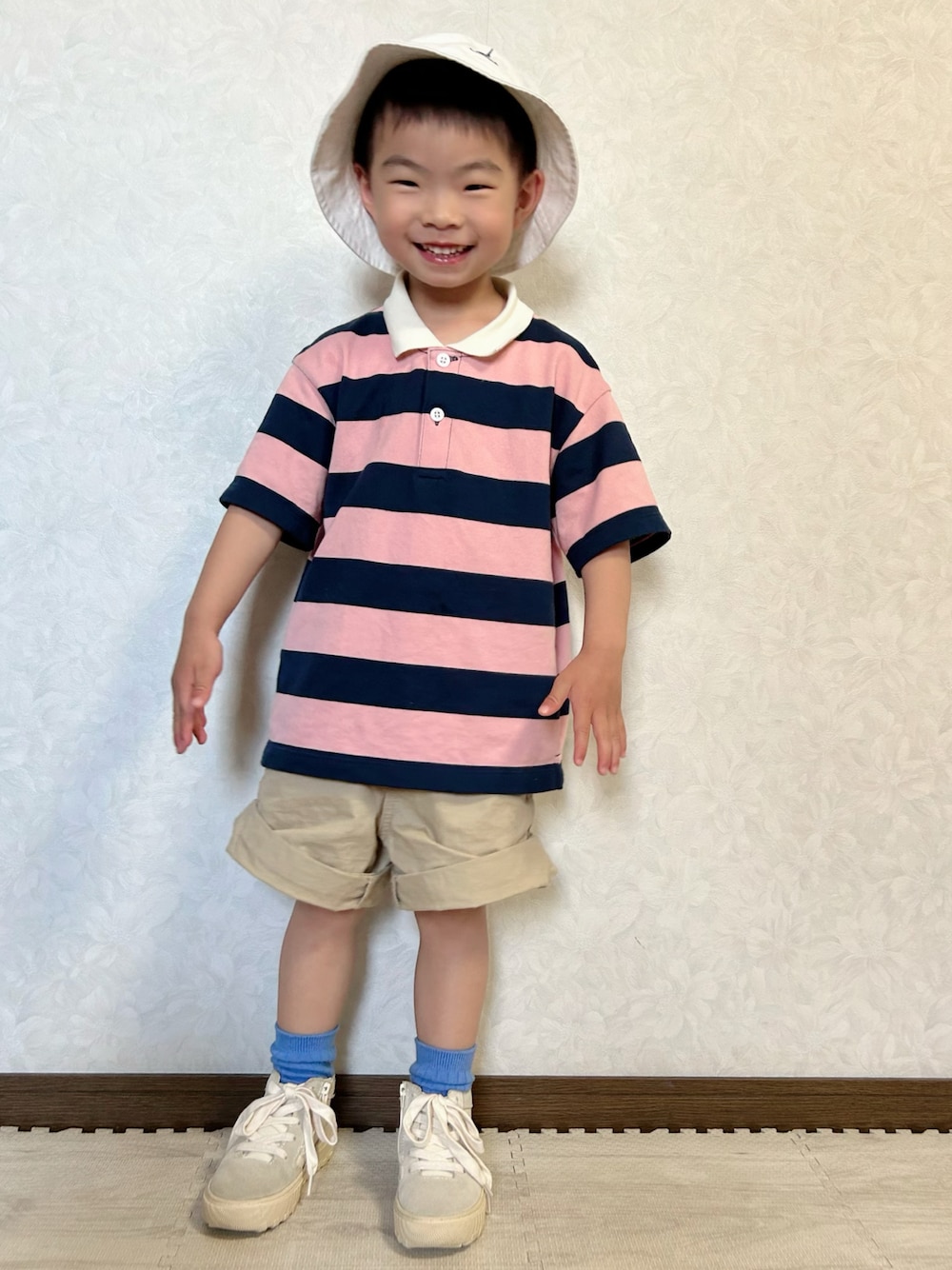 ピンク系のポロシャツ、ベージュ系のチノパンツ、ホワイト系のスニーカーを着用したキッズの春コーディネートの1枚目の写真
