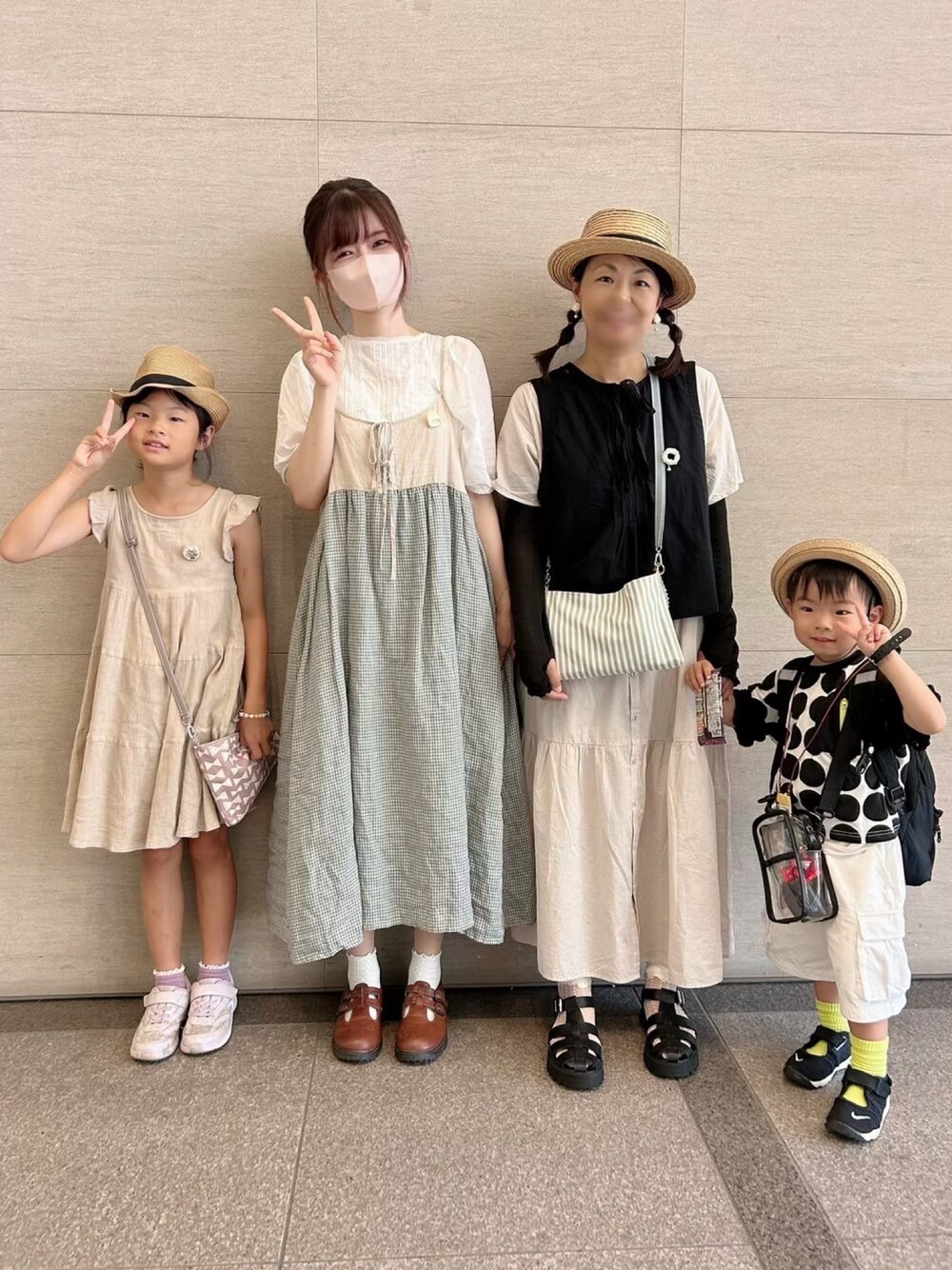 ホワイト系のワンピース、ブラック系のベスト、グリーン系のショルダーバッグを着用したキッズの夏コーディネートの1枚目の写真
