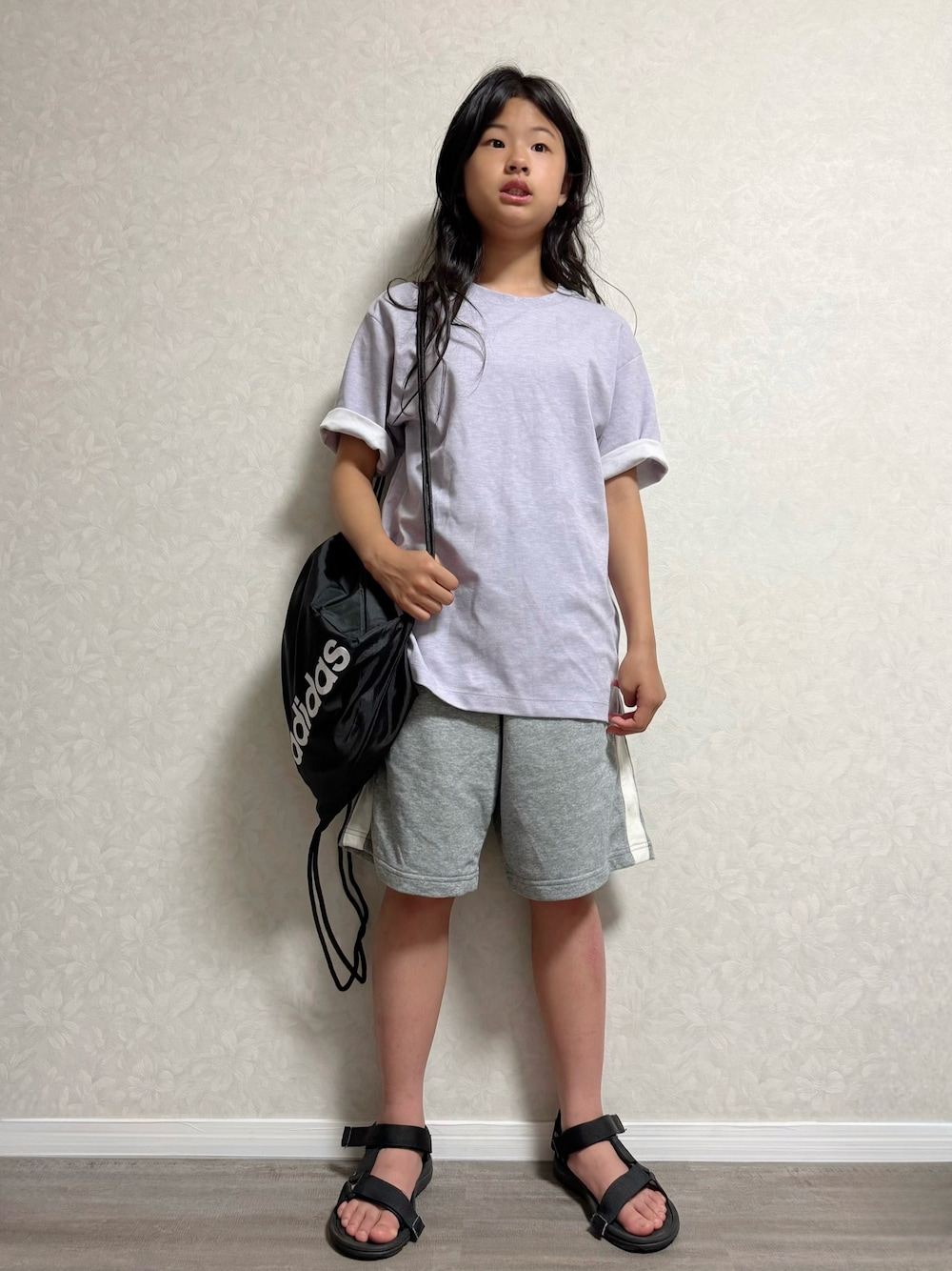 ブラック系のバックパック/リュック、ブラック系のサンダル、パープル系のTシャツ/カットソーを着用したキッズの夏コーディネートの1枚目の写真