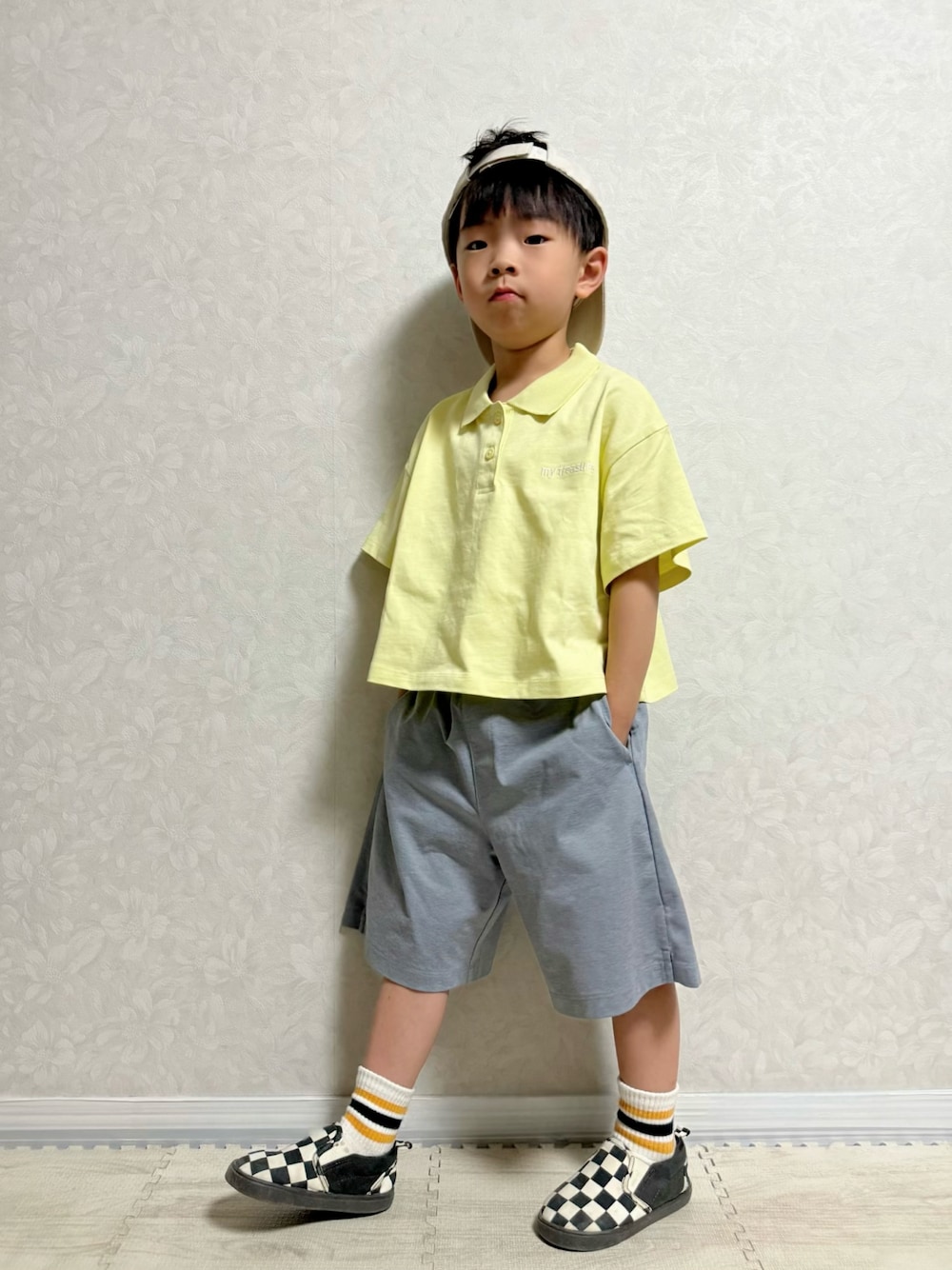イエロー系のポロシャツ、グレー系のパンツ、その他のスリッポンを着用したキッズの夏コーディネートの1枚目の写真