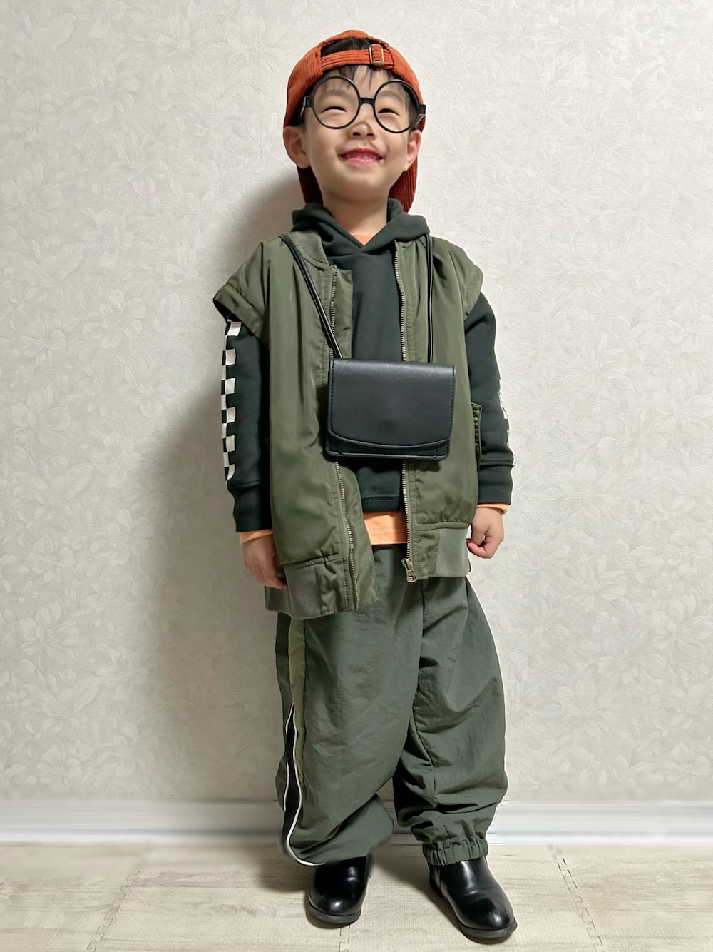 オレンジ系のTシャツ/カットソー、ブラック系のパーカー、グリーン系のMA-1を着用したキッズの秋コーディネートの1枚目の写真