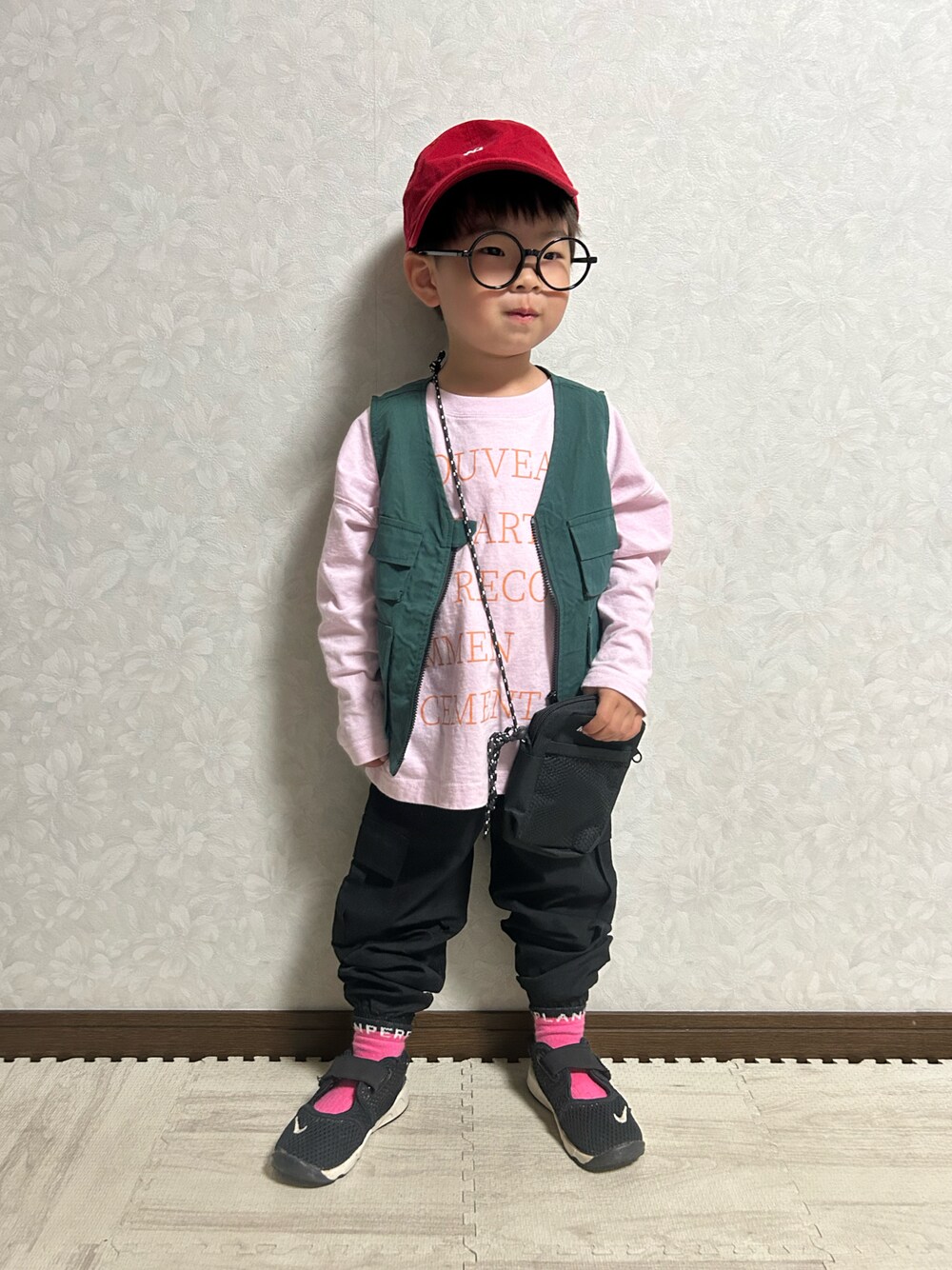 ピンク系のTシャツ/カットソー、グリーン系のベスト、ブラック系のショルダーバッグを着用したキッズの春コーディネートの1枚目の写真