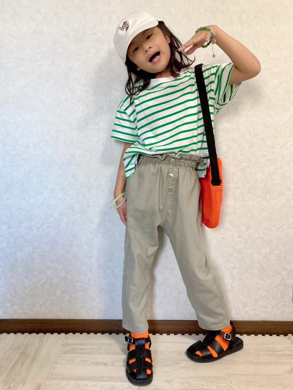 グリーン系のTシャツ/カットソー、グリーン系のパンツ、オレンジ系のショルダーバッグを着用したキッズの夏コーディネートの1枚目の写真