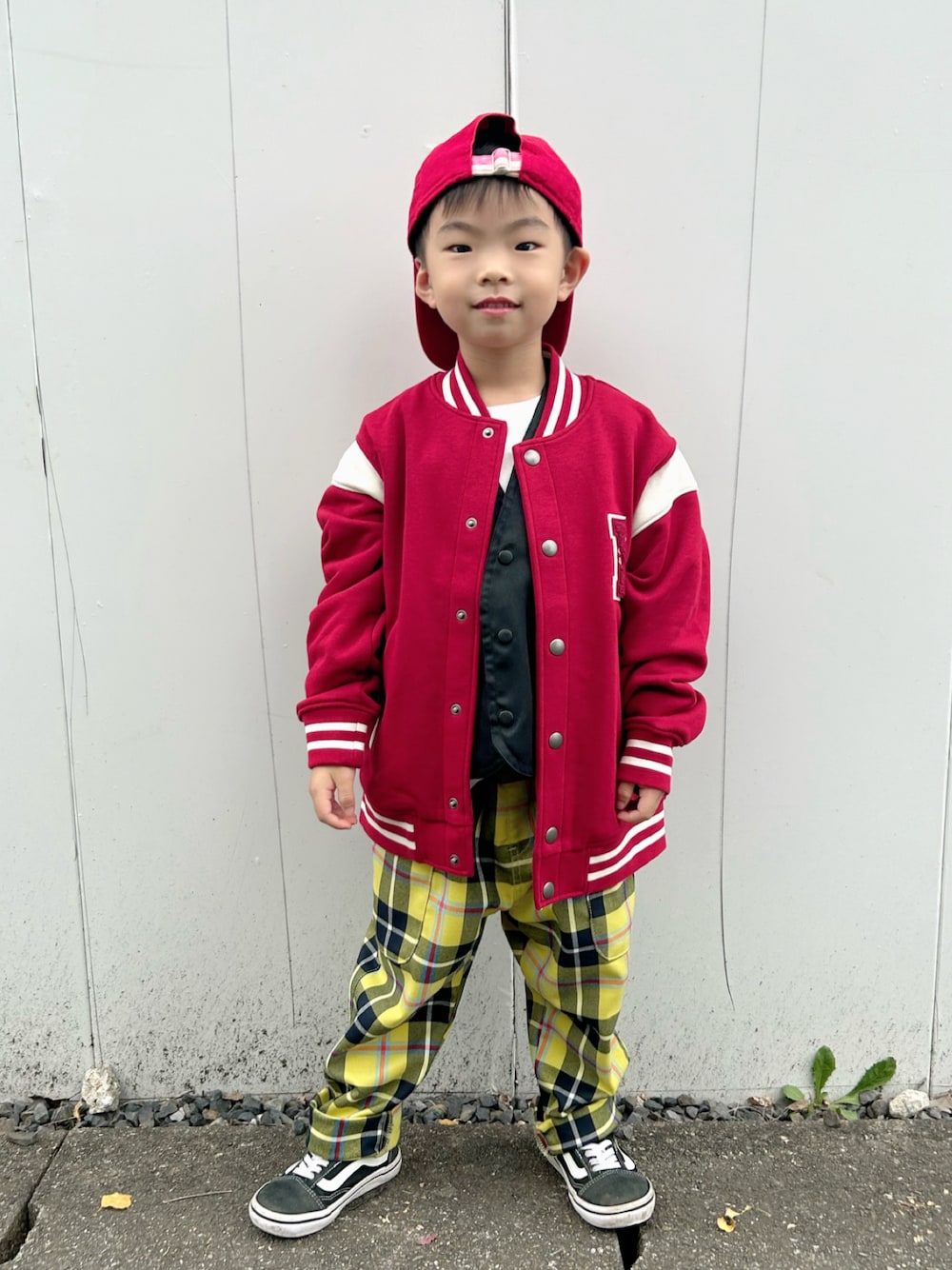 ホワイト系のTシャツ/カットソー、ブラック系のベスト、レッド系のスタジャンを着用したキッズの秋コーディネートの1枚目の写真