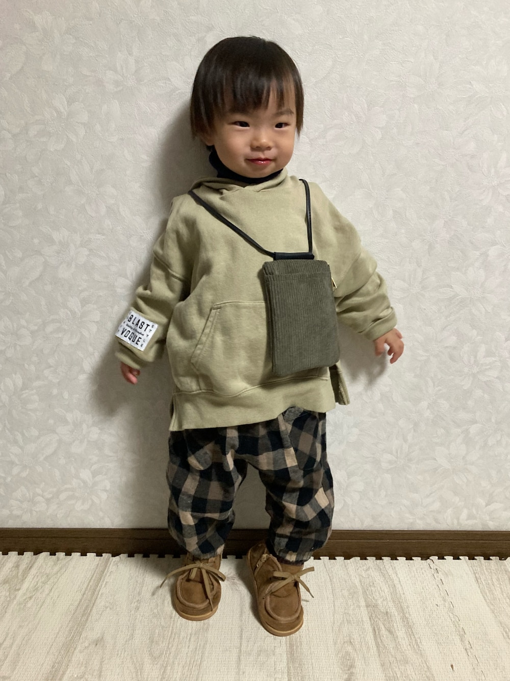 ベージュ系のパーカー、グリーン系のバッグ、ブルー系のニット/セーターを着用したキッズの秋コーディネートの1枚目の写真