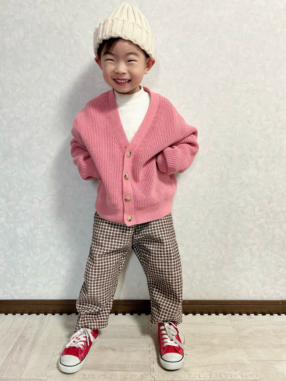ホワイト系のニット/セーター、ピンク系のカーディガン/ボレロ、ブラウン系のパンツを着用したキッズの冬コーディネートの1枚目の写真