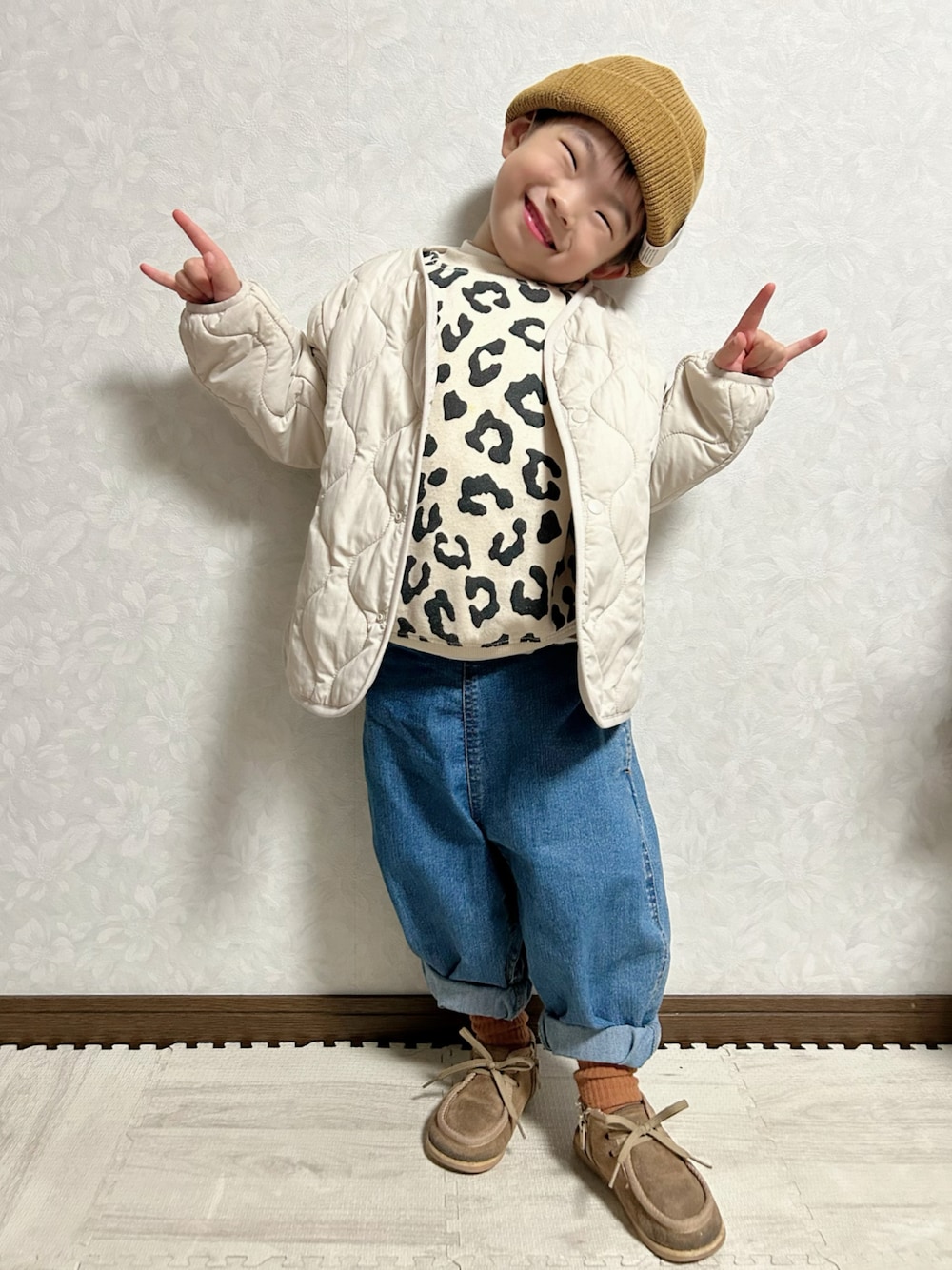 ベージュ系のスウェット、ホワイト系のノーカラージャケット、ブルー系のデニムパンツを着用したキッズの冬コーディネートの1枚目の写真