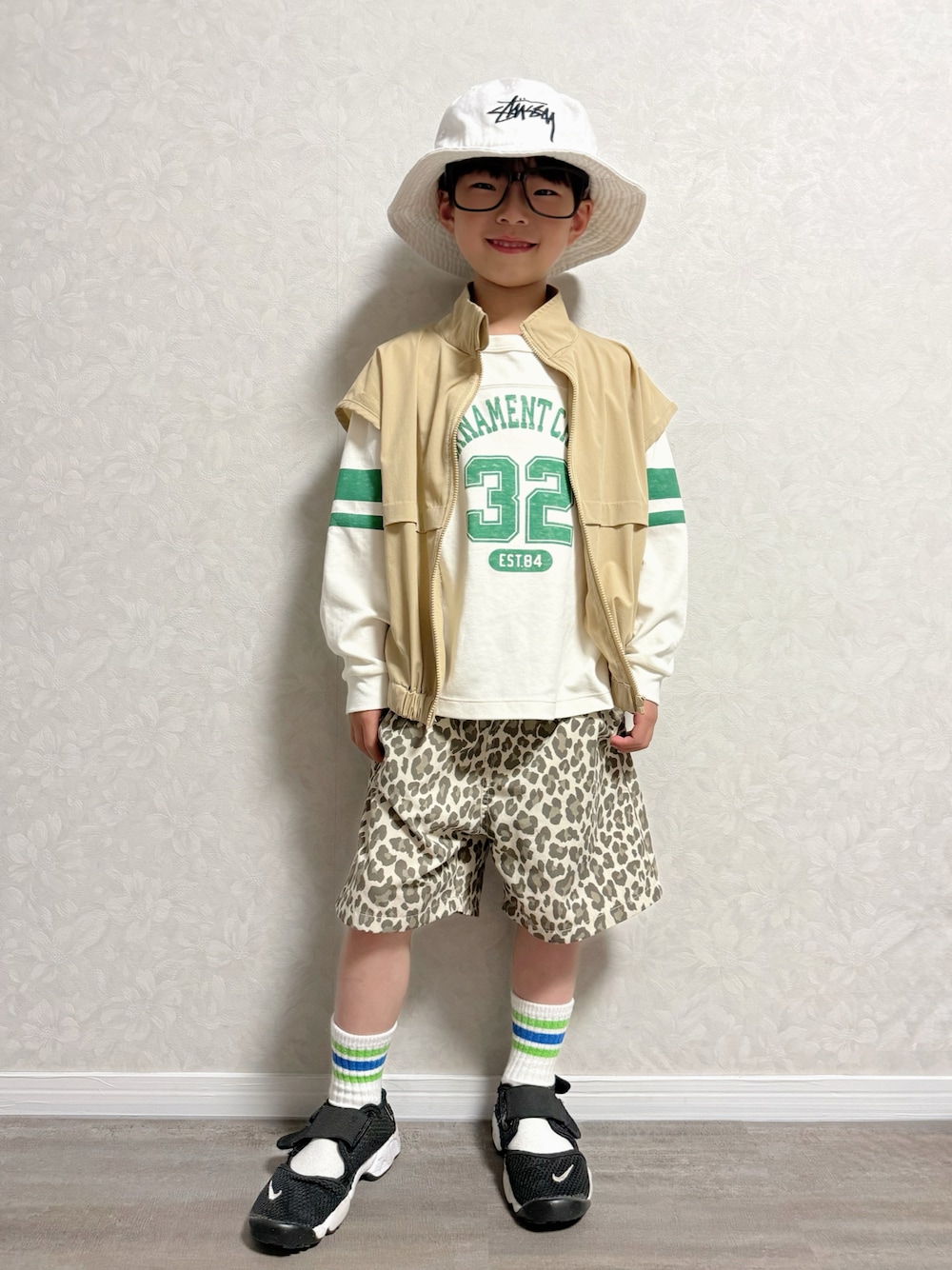 ベージュ系のその他パンツ、ホワイト系のショルダーバッグ、ブラック系のスニーカーを着用したキッズの春コーディネートの1枚目の写真