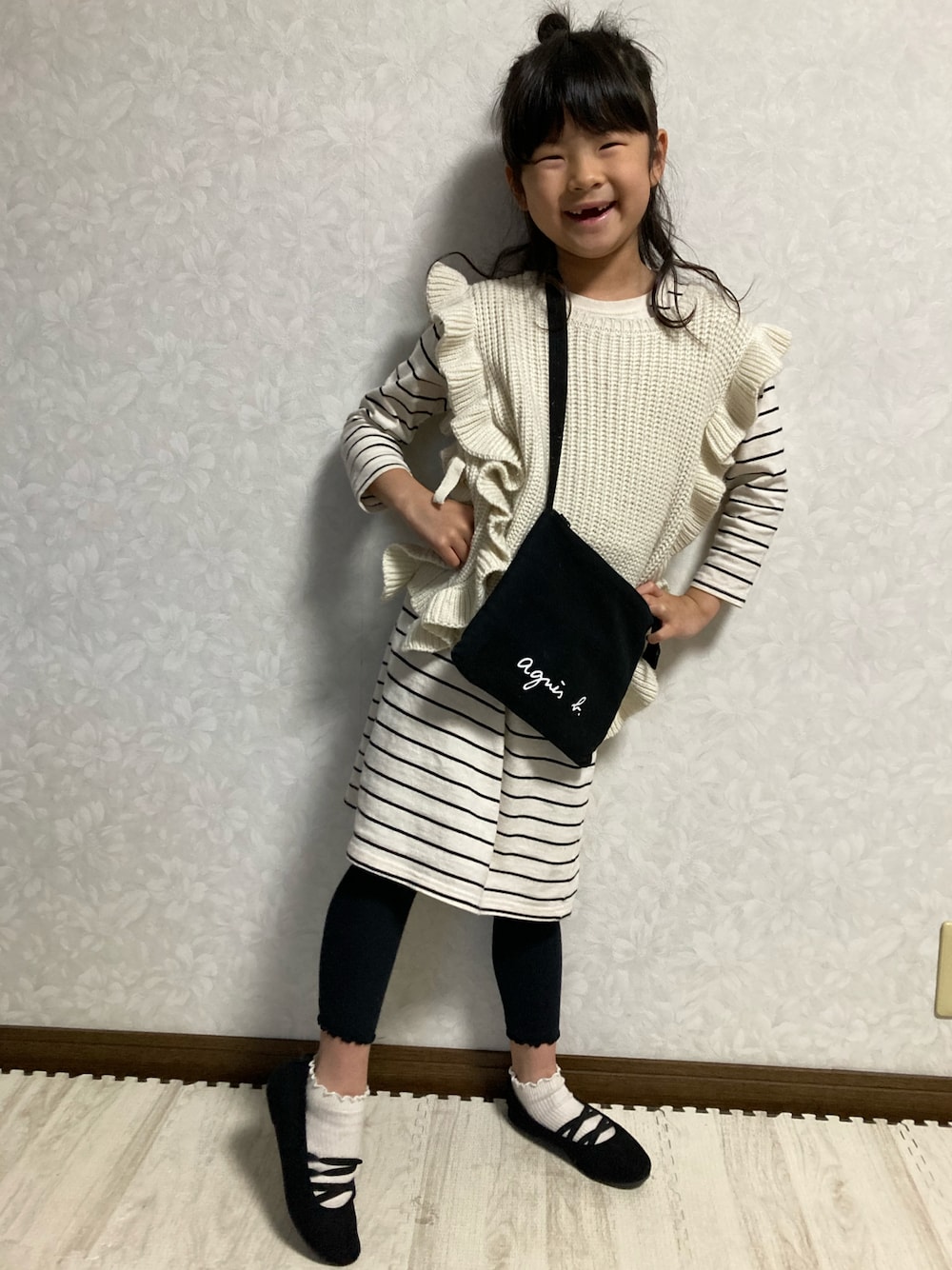 ブラック系のバレエシューズ、ホワイト系のワンピース、ベージュ系のベストを着用したキッズの春コーディネートの1枚目の写真