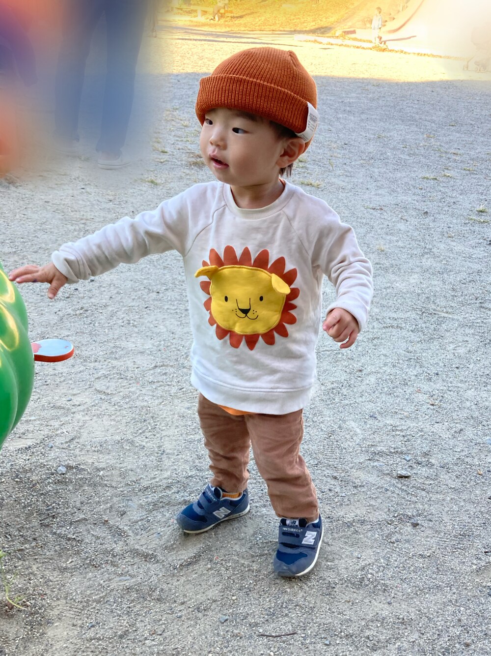 オレンジ系のタンクトップ、ベージュ系のスウェット、ブラウン系のパンツを着用したキッズの秋コーディネートの1枚目の写真