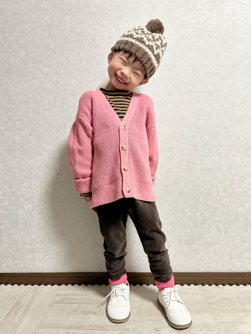 ピンク系のカーディガン/ボレロ、ブラウン系のTシャツ/カットソー、ホワイト系のドレスシューズを着用したキッズの冬コーディネートの1枚目の写真