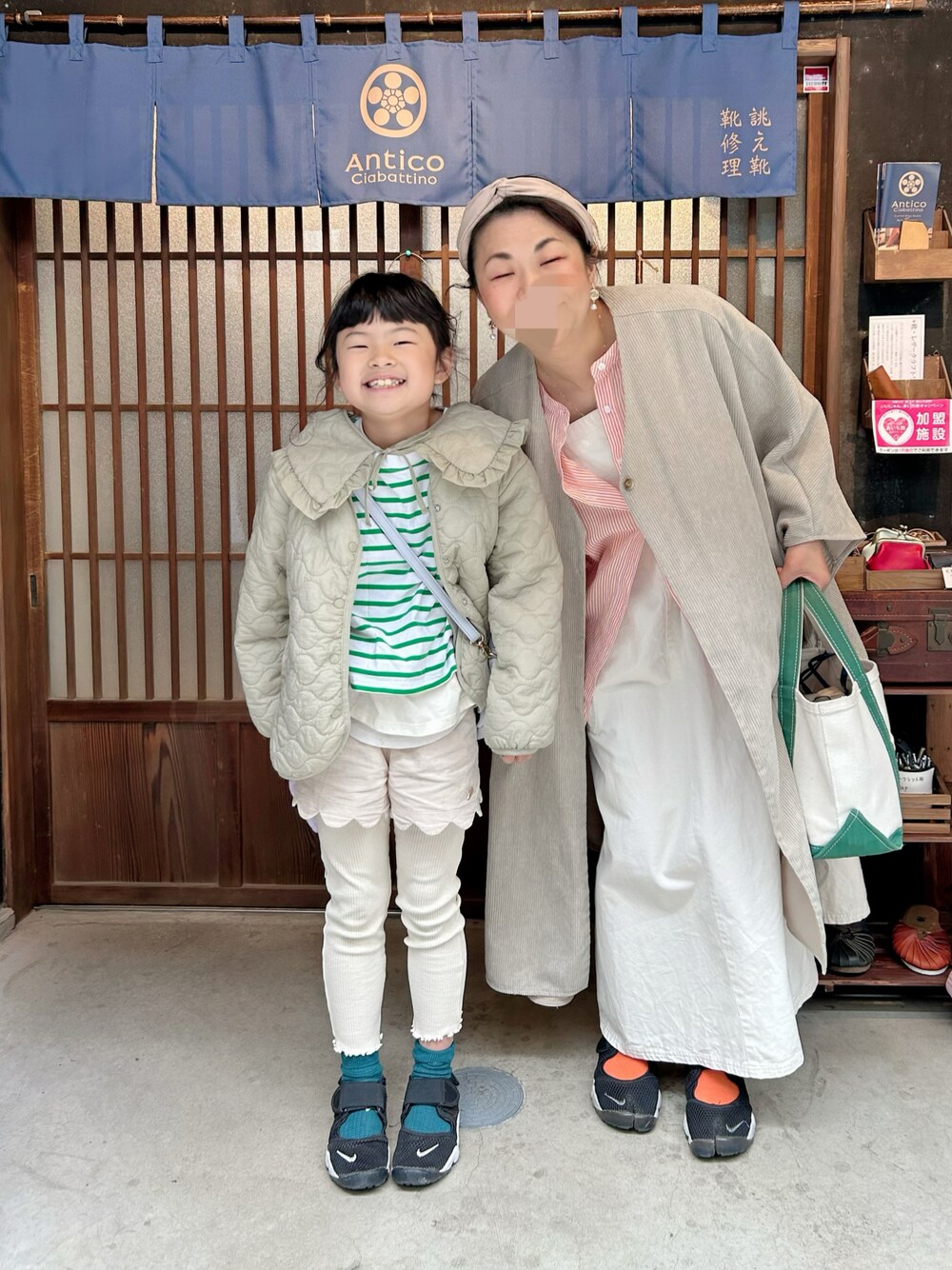 オレンジ系のシャツ/ブラウス、グリーン系のポンチョ、ホワイト系のジャンパースカートを着用したキッズの春コーディネートの1枚目の写真