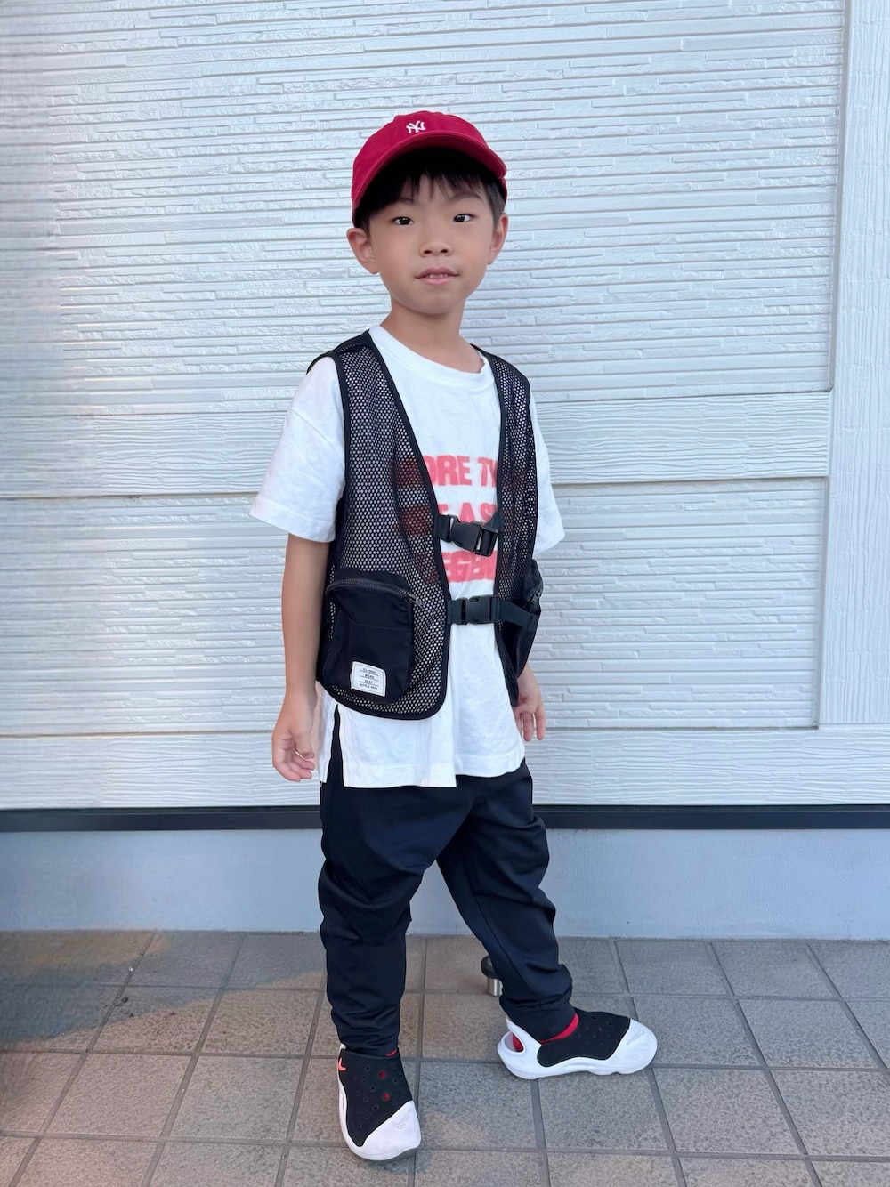 ホワイト系のTシャツ/カットソー、ホワイト系のサンダル、ブラック系のベストを着用したキッズの夏コーディネートの1枚目の写真