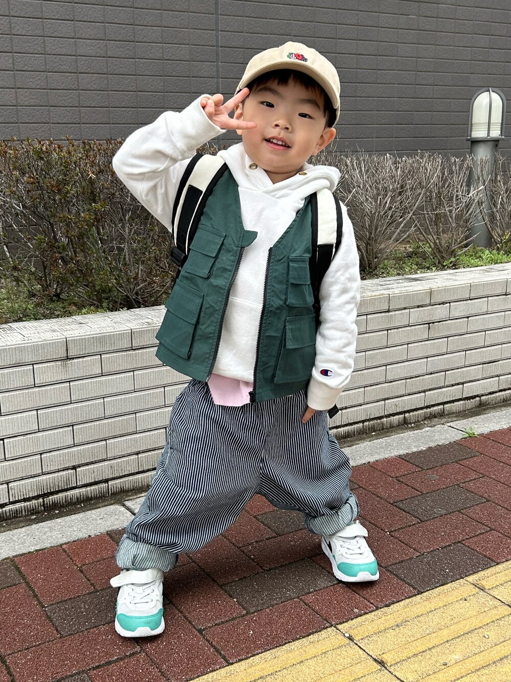 ピンク系のTシャツ/カットソー、ホワイト系のパーカー、グリーン系のベストを着用したキッズの春コーディネートの1枚目の写真