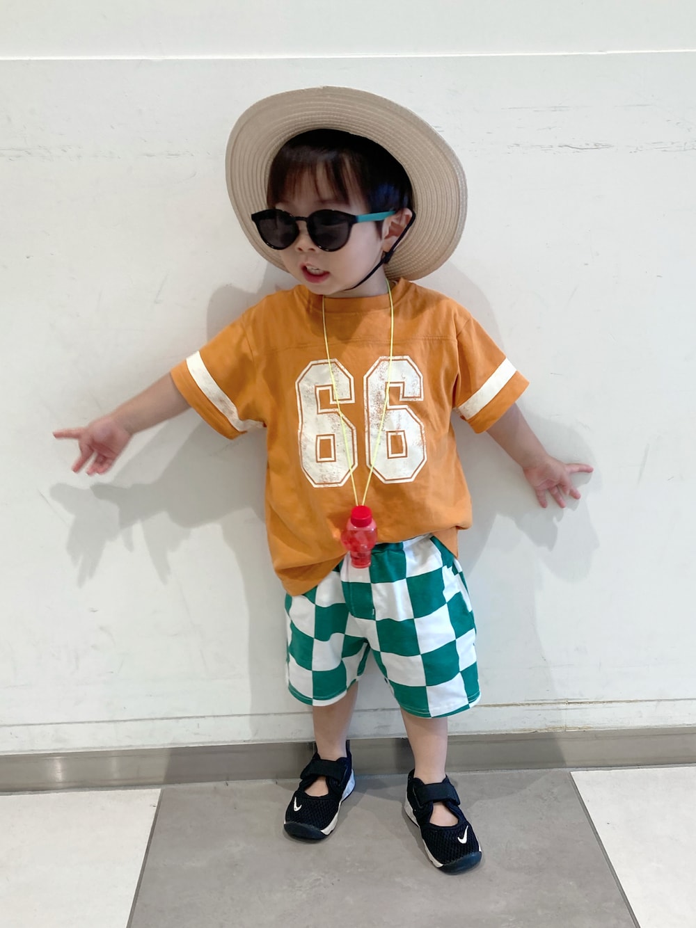 オレンジ系のTシャツ/カットソー、グリーン系のパンツ、ブラック系のサンダルを着用したキッズの夏コーディネートの1枚目の写真