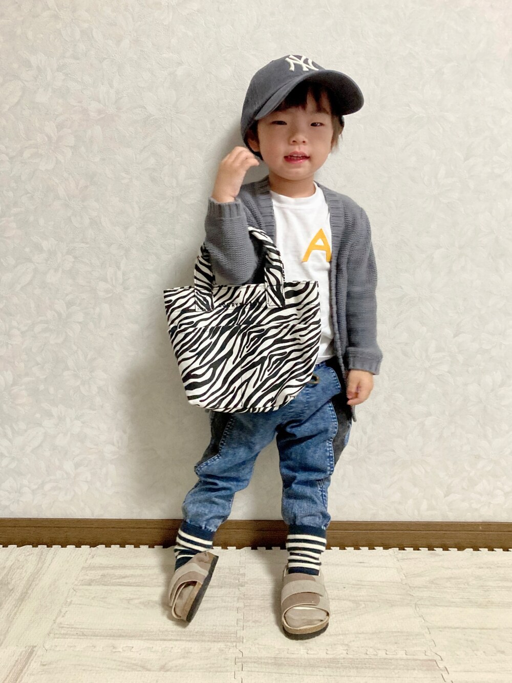 グレー系のカーディガン/ボレロ、ブルー系のデニムパンツ、その他のトートバッグを着用したキッズの秋コーディネートの1枚目の写真