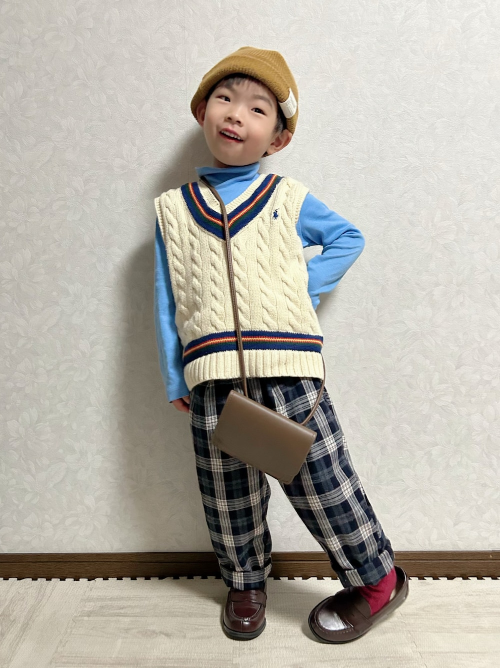 ブルー系のTシャツ/カットソー、ホワイト系のベスト、ブラウン系のショルダーバッグを着用したキッズの冬コーディネートの1枚目の写真