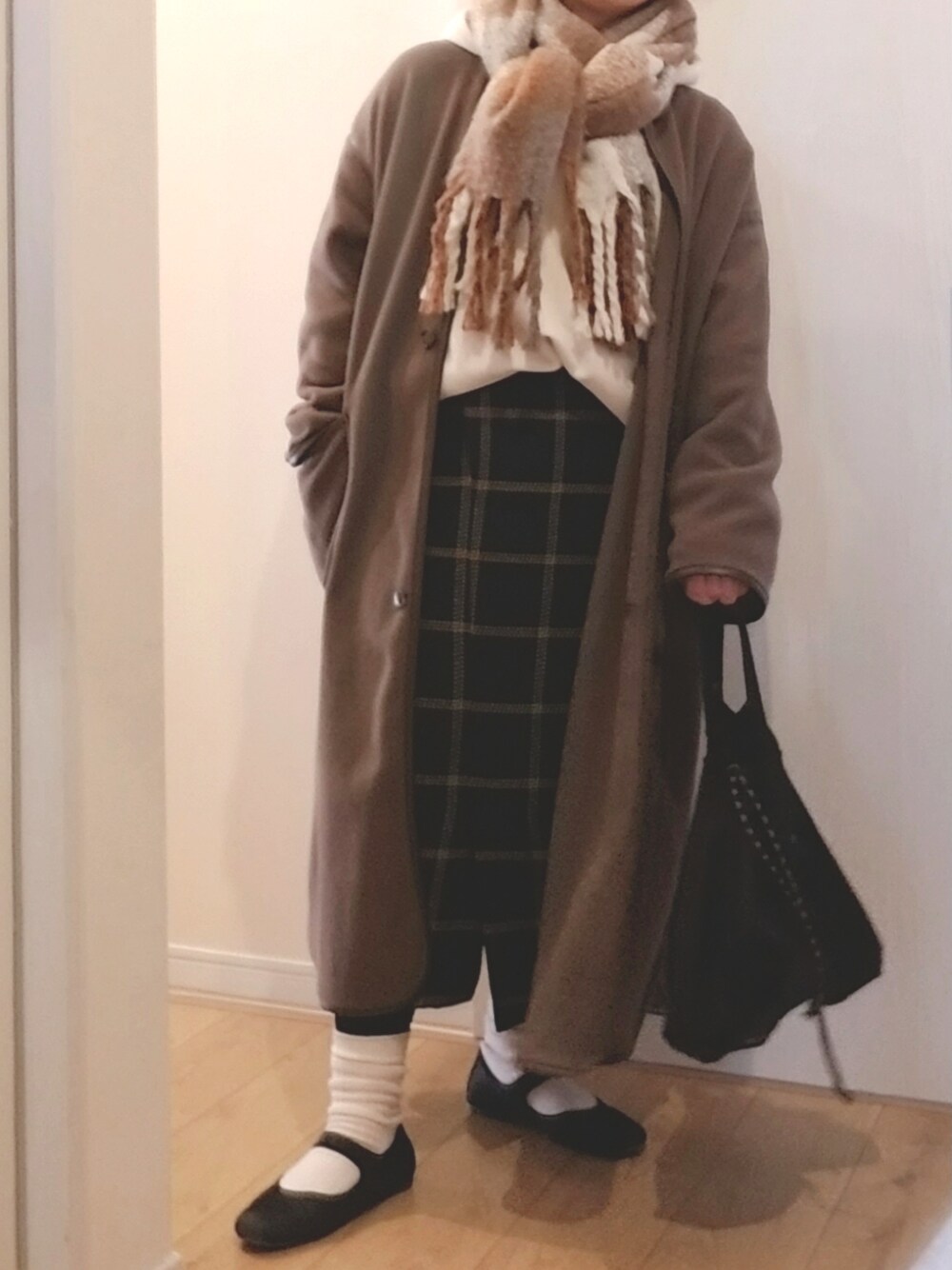 グリーン系のスカート、ブラック系のバッグ、ブラウン系のノーカラーコートを着用したレディースの冬コーディネートの1枚目の写真