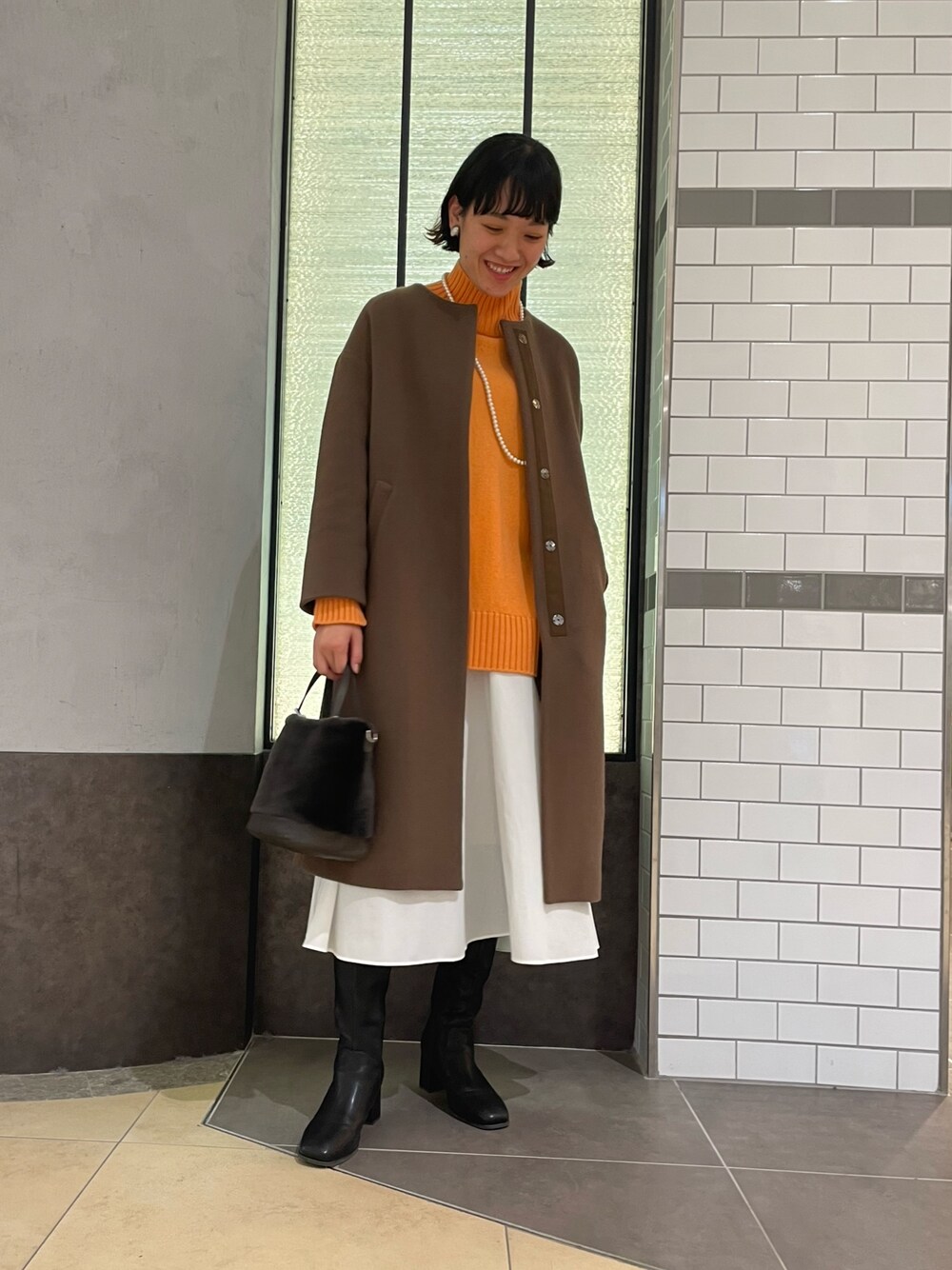 「オレンジニット、冬コーデ、コート、NOLLEY'S、ノーリーズ、ブラウンコート、ウールコート、ロングコート、ハイネックニット、白スカート、ロングブーツ、大人カジュアル」｜「NOLLEY’Sのコットンパールネックレス 100cm（ネックレス、ホワイト系）」を使った、fukudaさん（レディース・170cm）の冬コーディネートの1枚目の写真