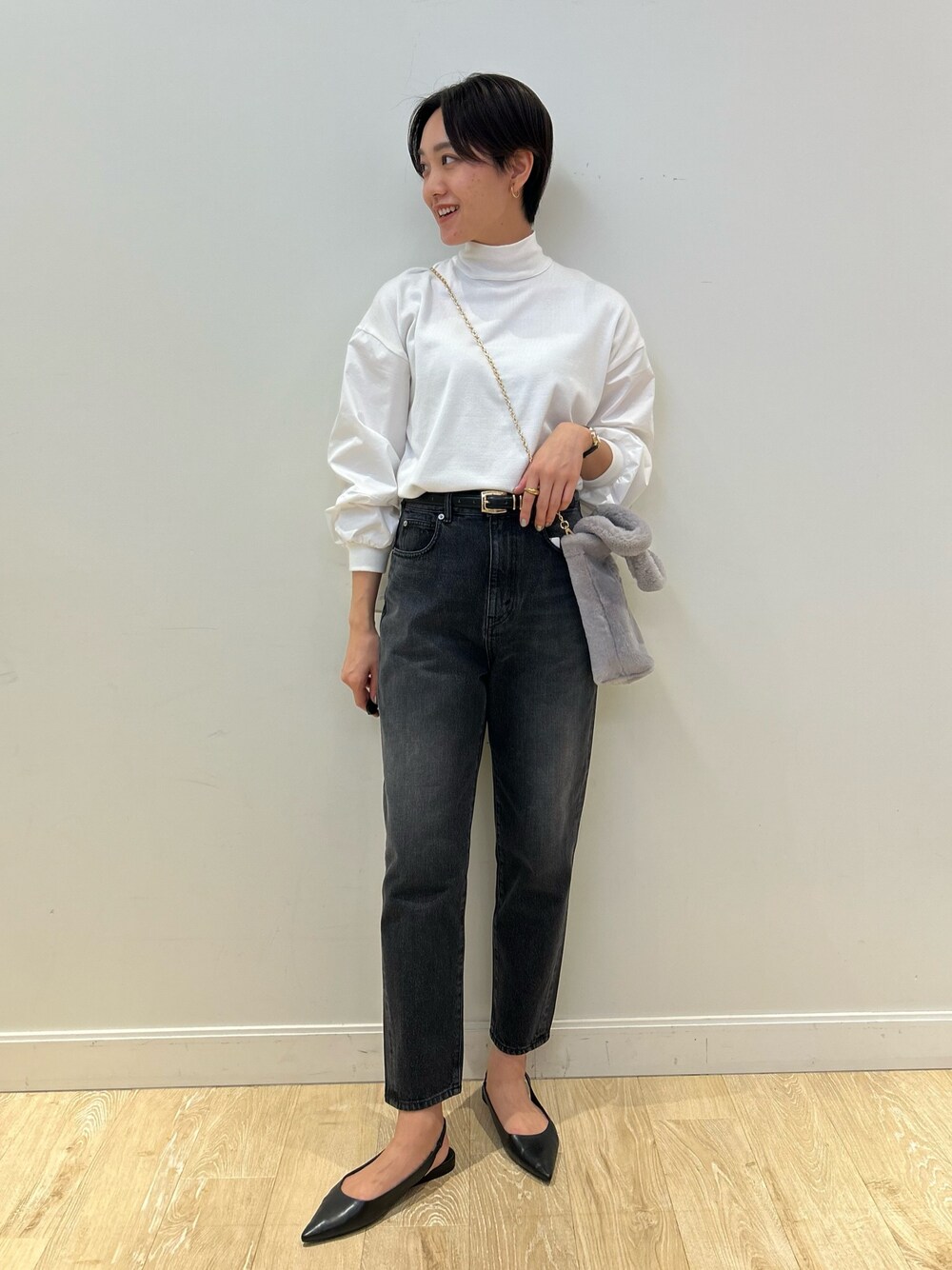 グレー系のトートバッグ、ブラック系のデニムパンツ、ブラック系のベルトを着用したレディースの冬コーディネートの1枚目の写真