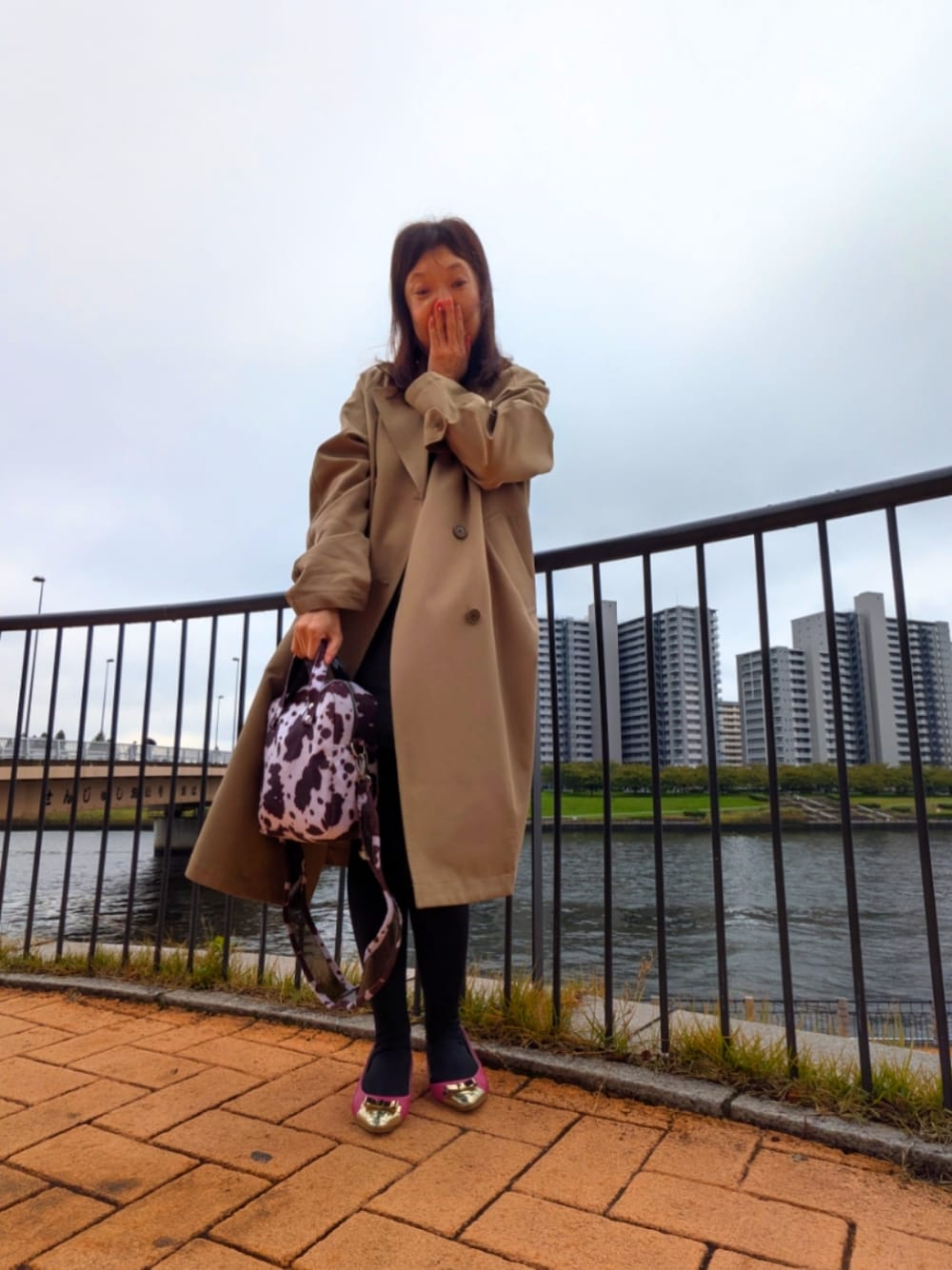 ベージュ系のニット/セーター、ベージュ系のトレンチコート、ブラウン系のスカートを着用したレディースの秋コーディネートの1枚目の写真