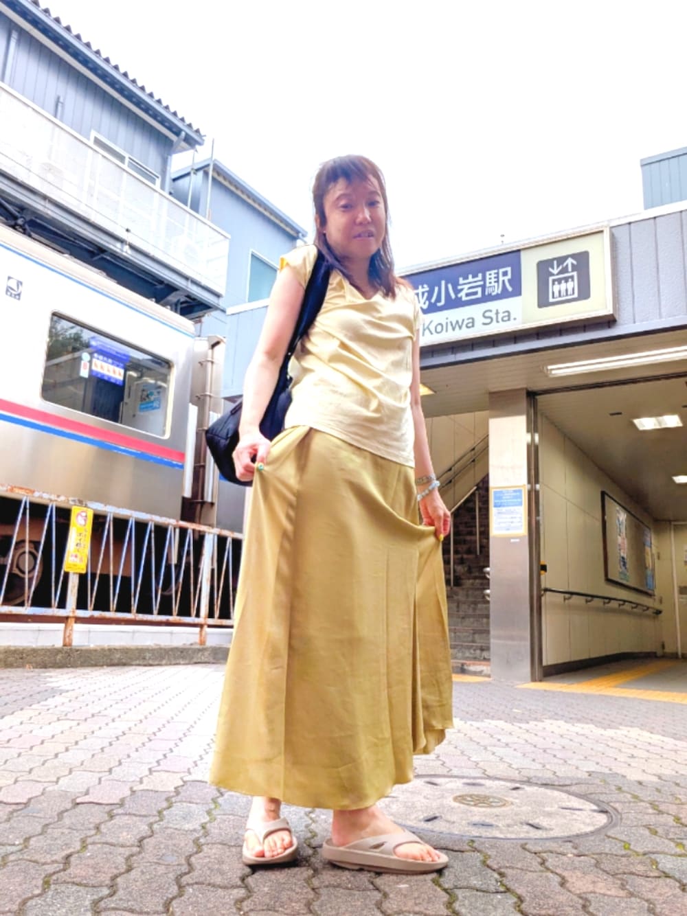 ブラック系のショルダーバッグ、イエロー系のTシャツ/カットソー、イエロー系のスカートを着用したレディースの夏コーディネートの1枚目の写真
