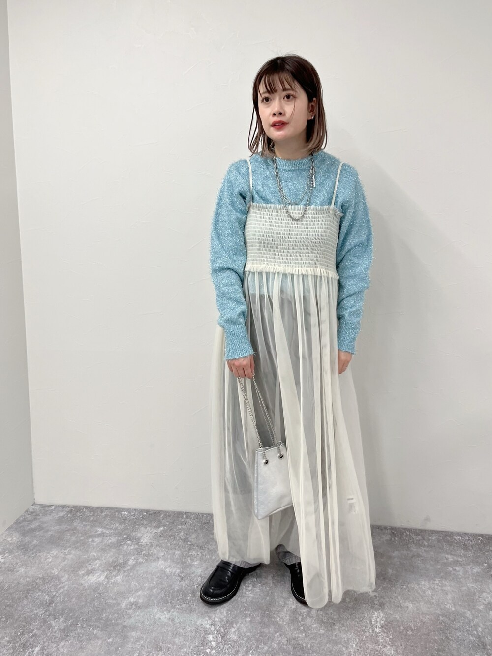 ホワイト系のワンピース、ブルー系のニット/セーター、ブラック系のデニムパンツを着用したレディースの冬コーディネートの1枚目の写真