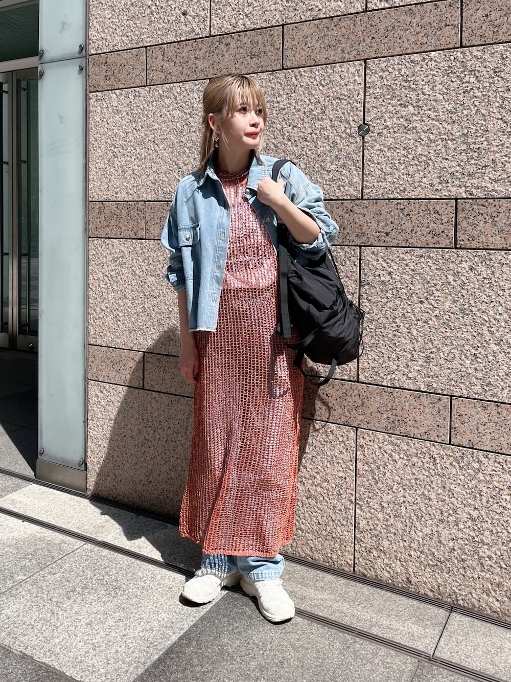 ブラウン系のニット/セーター、ブルー系のシャツ/ブラウス、ブラック系のバックパック/リュックを着用したレディースの春コーディネートの1枚目の写真