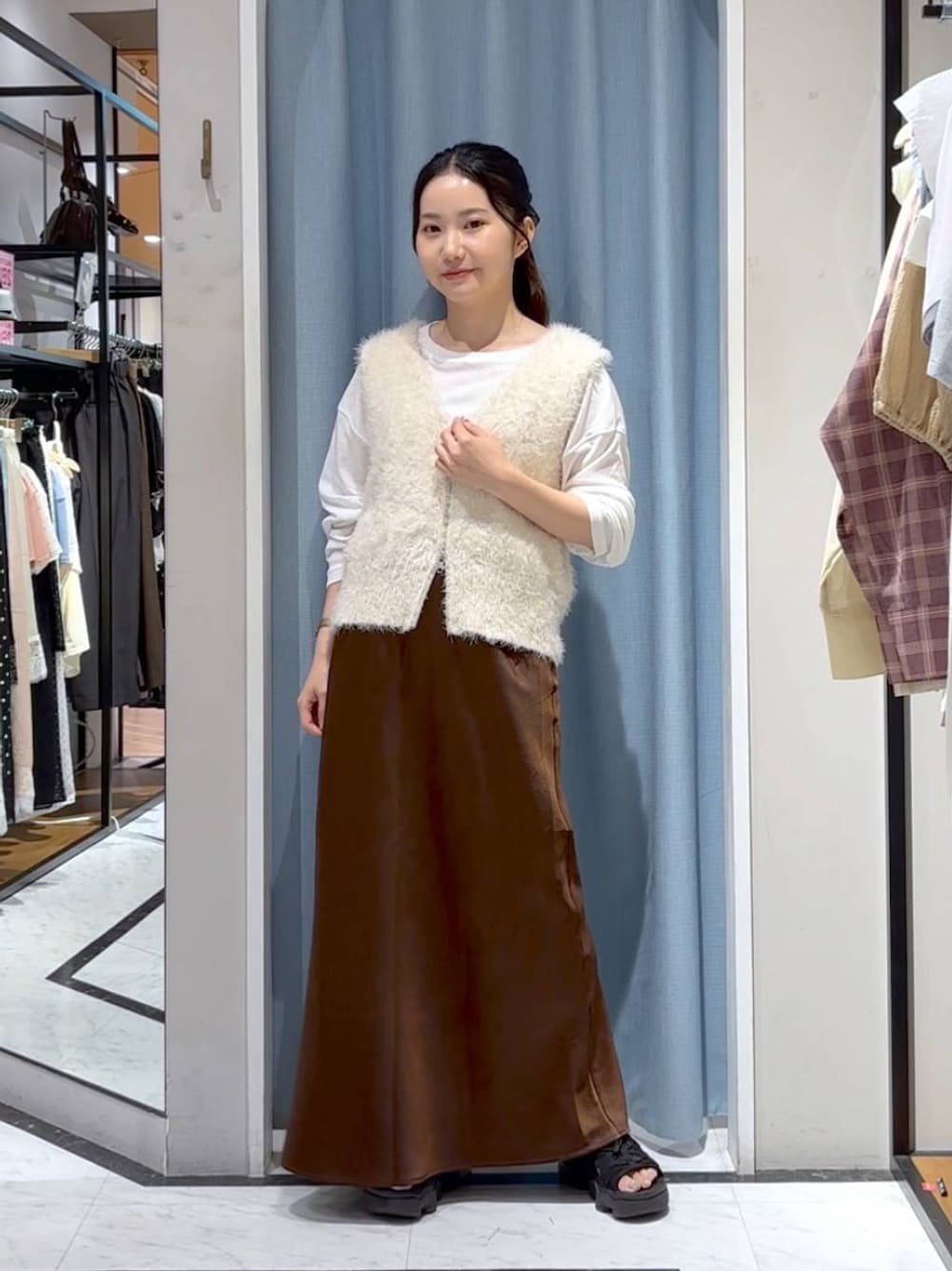 ブラウン系のスカート、ホワイト系のTシャツ/カットソー、ホワイト系のベストを着用したレディースの秋コーディネートの1枚目の写真