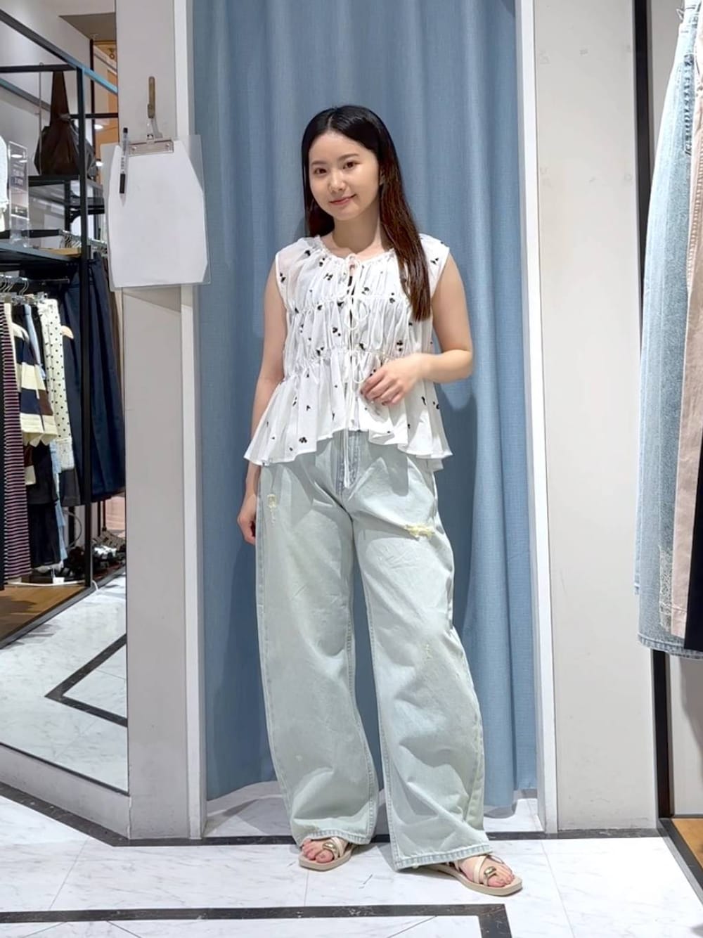 ブルー系のデニムパンツ、ホワイト系のサンダル、ホワイト系のシャツ/ブラウスを着用したレディースの夏コーディネートの1枚目の写真