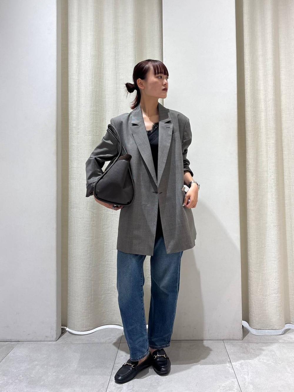 ブラウン系のテーラードジャケット、ブルー系のデニムパンツ、ブラウン系のボストンバッグを着用したレディースの秋コーディネートの1枚目の写真