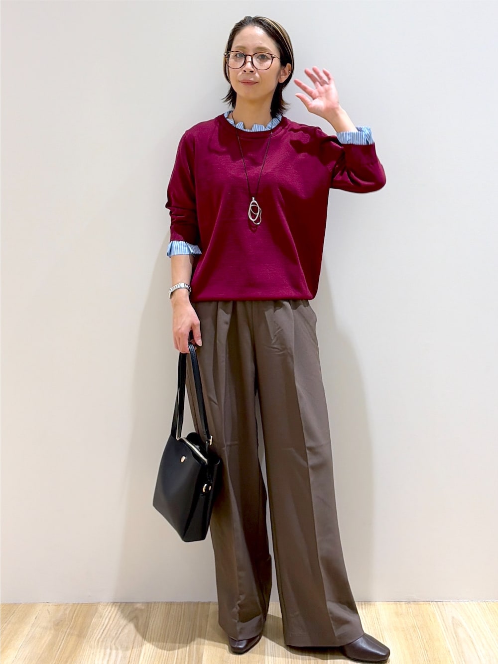 レッド系のニット/セーター、ブラウン系のその他パンツ、ブラック系のショルダーバッグを着用したレディースの秋コーディネートの1枚目の写真