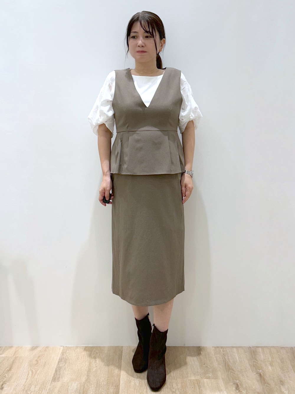 ブラウン系のワンピース、ホワイト系のTシャツ/カットソー、ブラウン系のブーツを着用したレディースの秋コーディネートの1枚目の写真