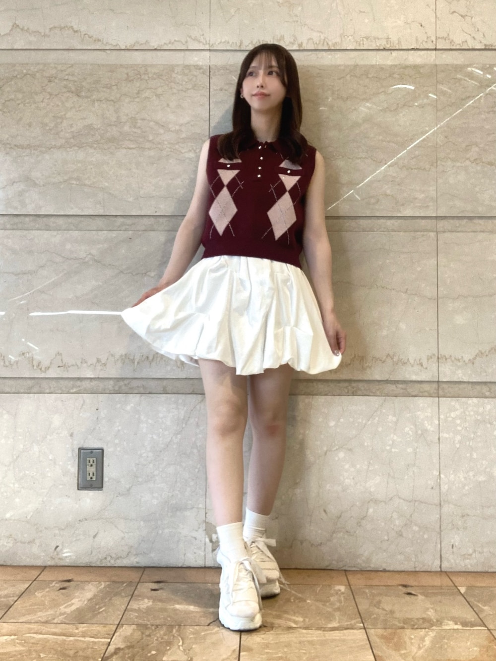 レッド系のニット/セーター、ホワイト系のスカート、ホワイト系のサンダルを着用したレディースの夏コーディネートの1枚目の写真