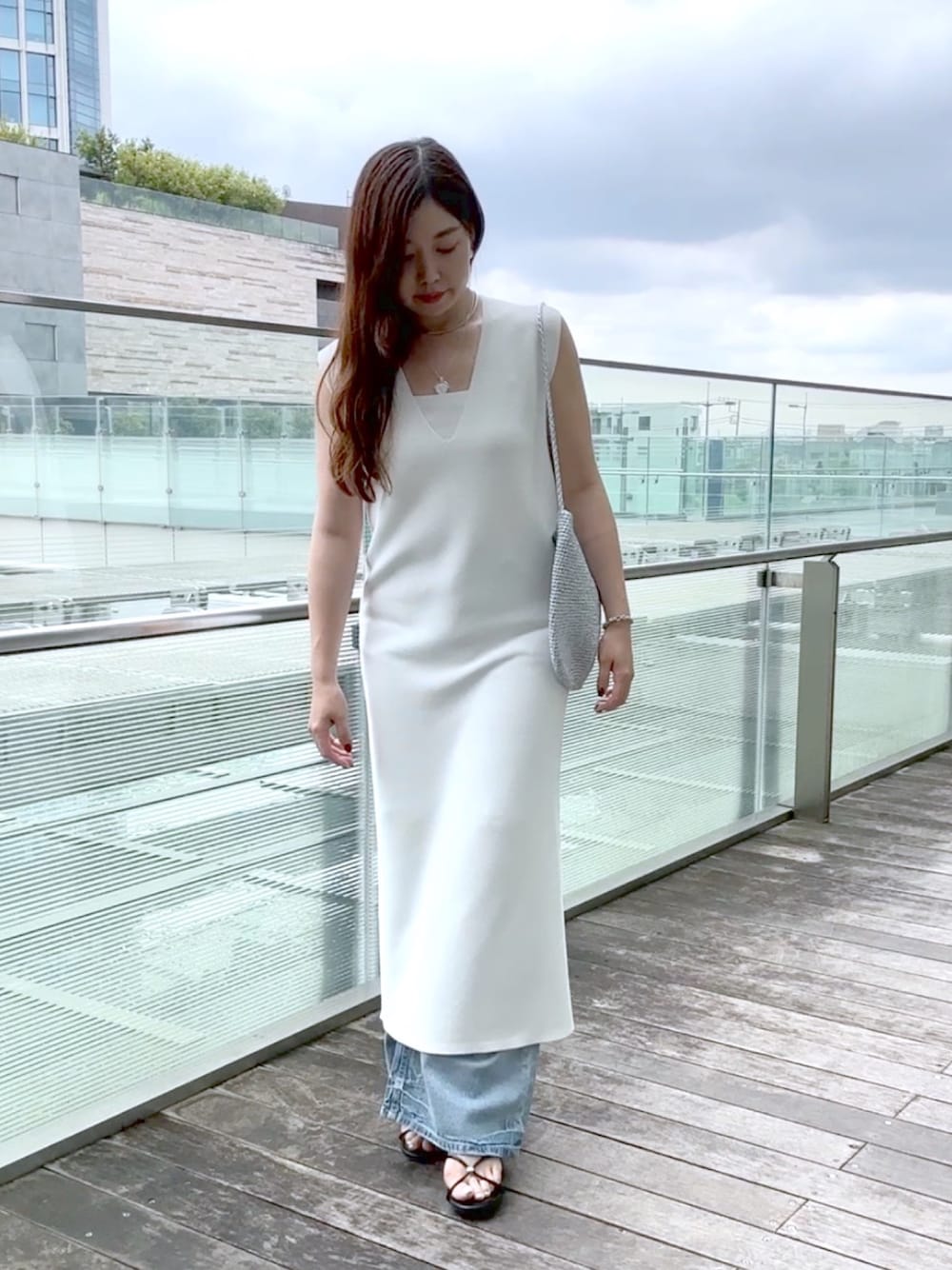 ホワイト系のワンピース、ブルー系のデニムパンツ、シルバー系のショルダーバッグを着用したレディースの夏コーディネートの1枚目の写真