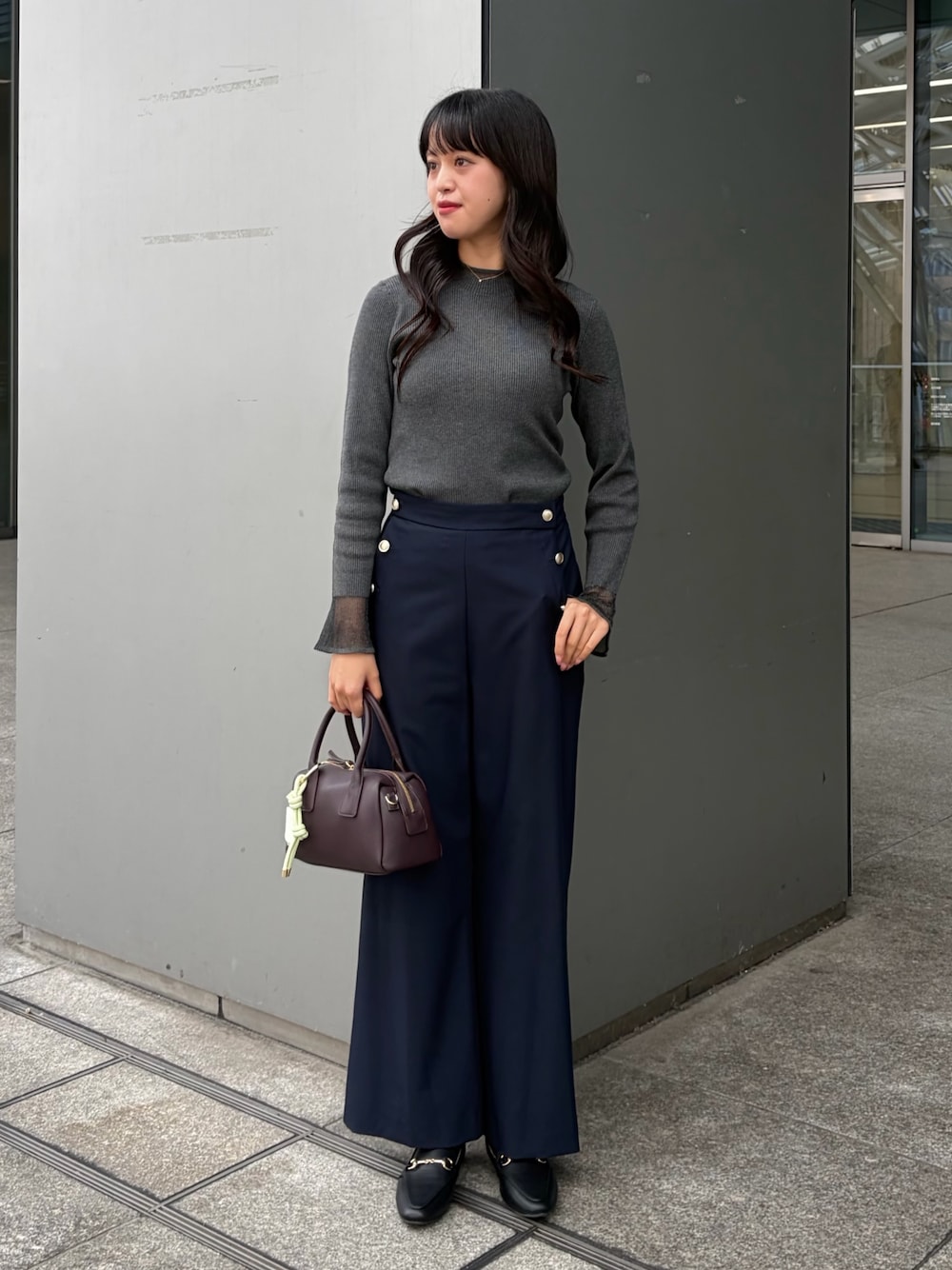 グレー系のニット/セーター、ブルー系のその他パンツ、ブラウン系のボストンバッグを着用したレディースの秋コーディネートの1枚目の写真