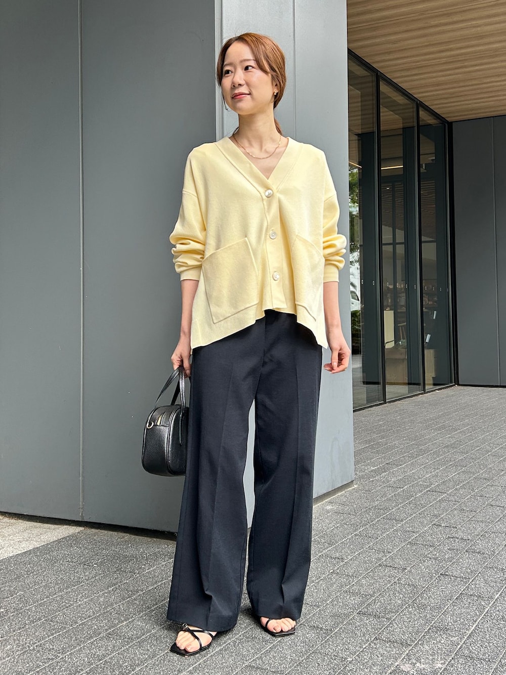 ブラック系のその他パンツ、イエロー系のカーディガン/ボレロ、ブラック系のボストンバッグを着用したレディースの春コーディネートの1枚目の写真