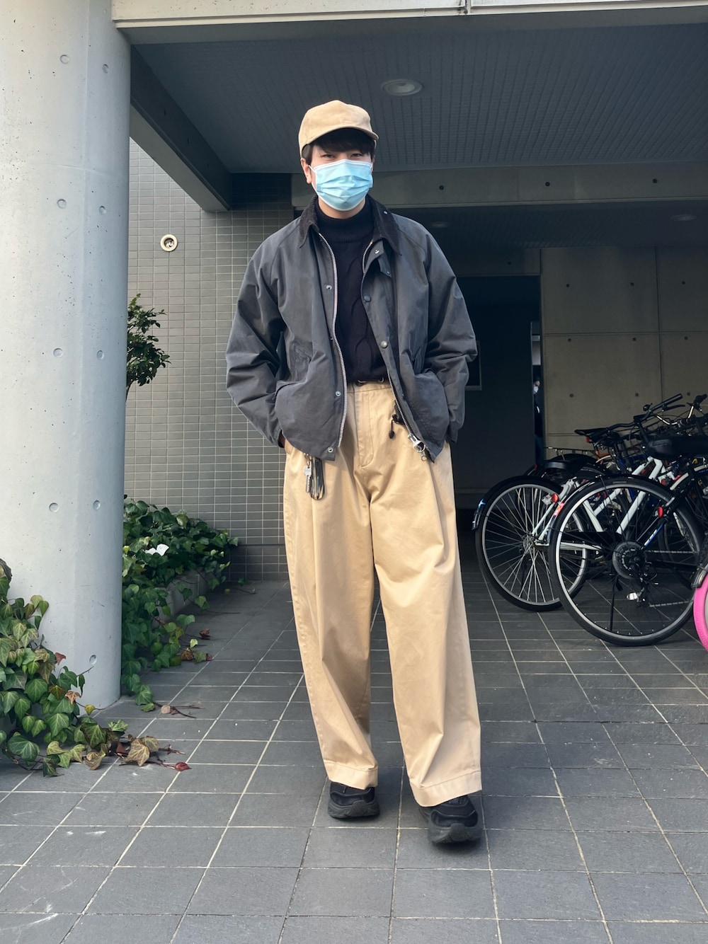 グレー系のブルゾン、ブルー系のニット/セーター、ベージュ系のチノパンツを着用したメンズの冬コーディネートの1枚目の写真