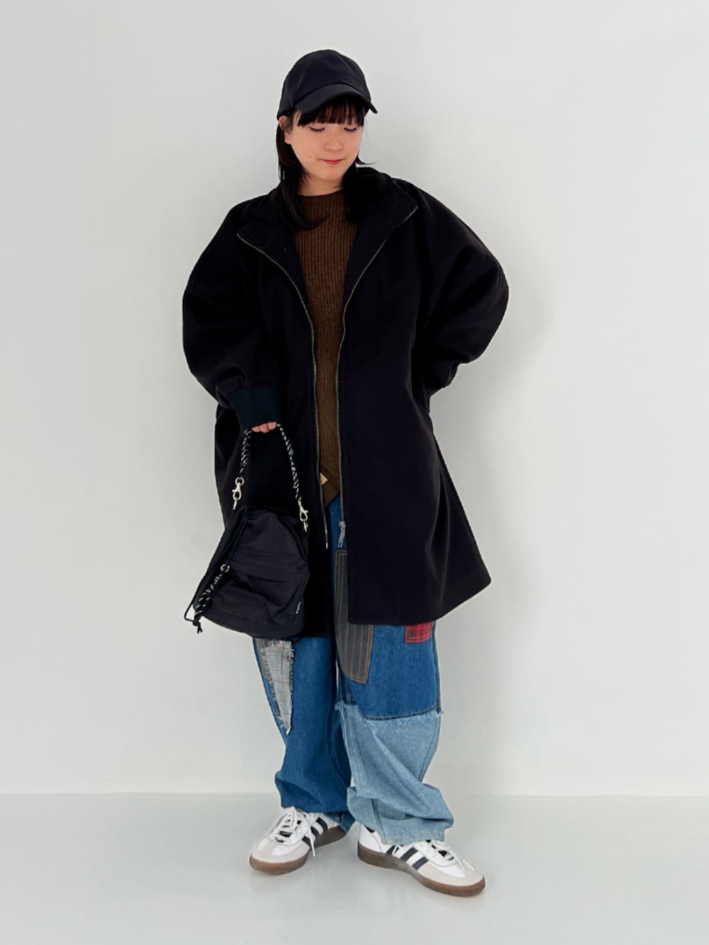 グリーン系のニット/セーター、ブラック系のその他アウター、ブルー系のデニムパンツを着用したレディースの冬コーディネートの1枚目の写真