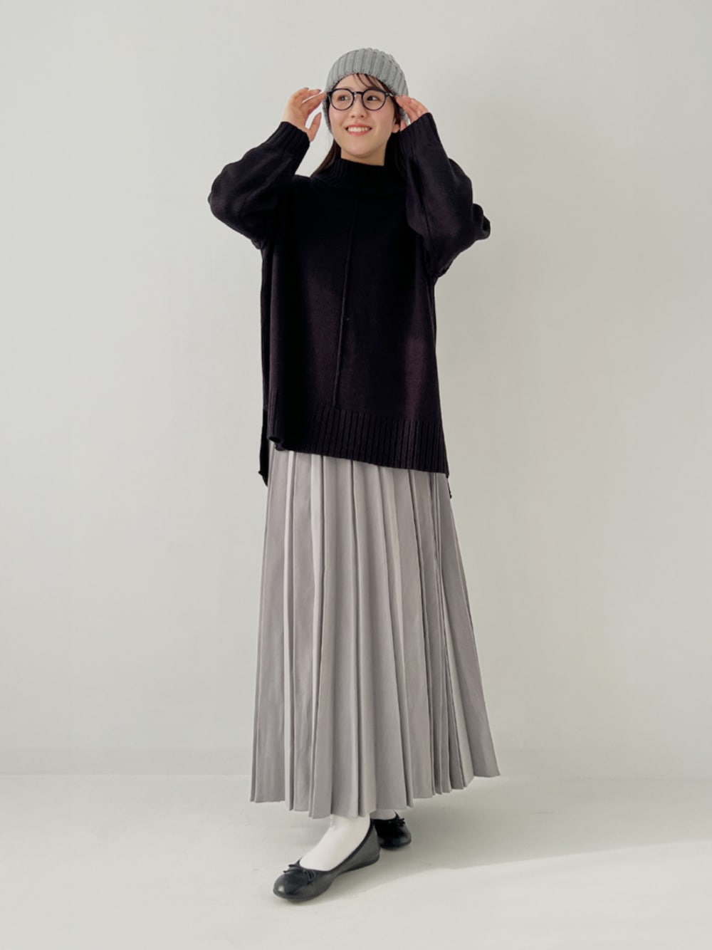 グレー系のスカート、ブラック系のニット/セーターを着用したレディースの冬コーディネートの1枚目の写真