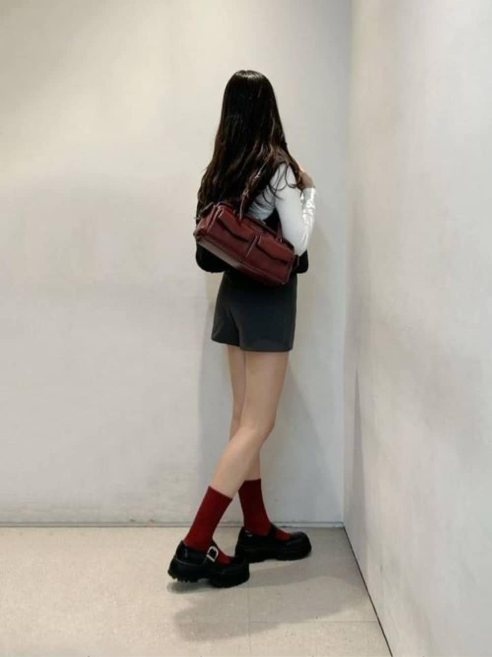 レッド系のショルダーバッグ、ブラック系のパンプスを着用したレディースの秋コーディネートの1枚目の写真