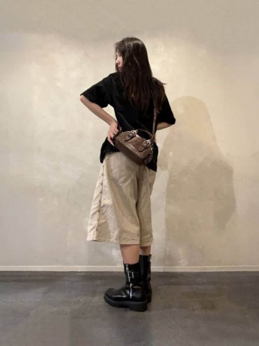 ブラウン系のトートバッグ、ブラック系のブーツを着用したレディースの秋コーディネートの1枚目の写真