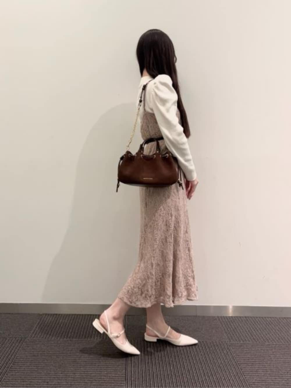 ホワイト系のパンプス、ブラウン系のショルダーバッグを着用したレディースの春コーディネートの1枚目の写真