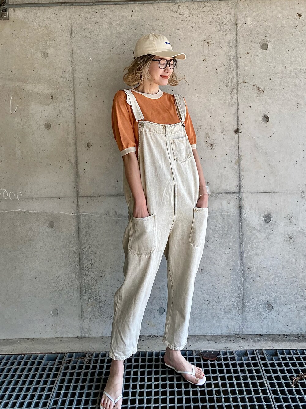 オレンジ系のニット/セーター、ホワイト系のサンダル、ホワイト系のサロペット/オーバーオールを着用したレディースの春コーディネートの1枚目の写真