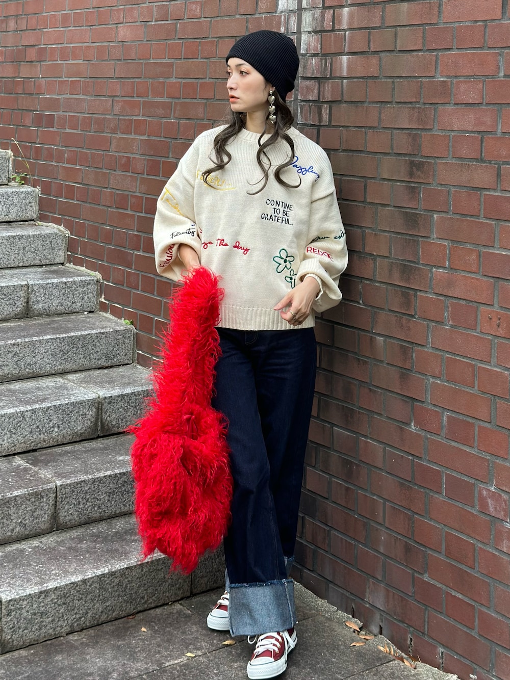 ホワイト系のニット/セーター、ブルー系のデニムパンツ、レッド系のトートバッグを着用したレディースの秋コーディネートの1枚目の写真