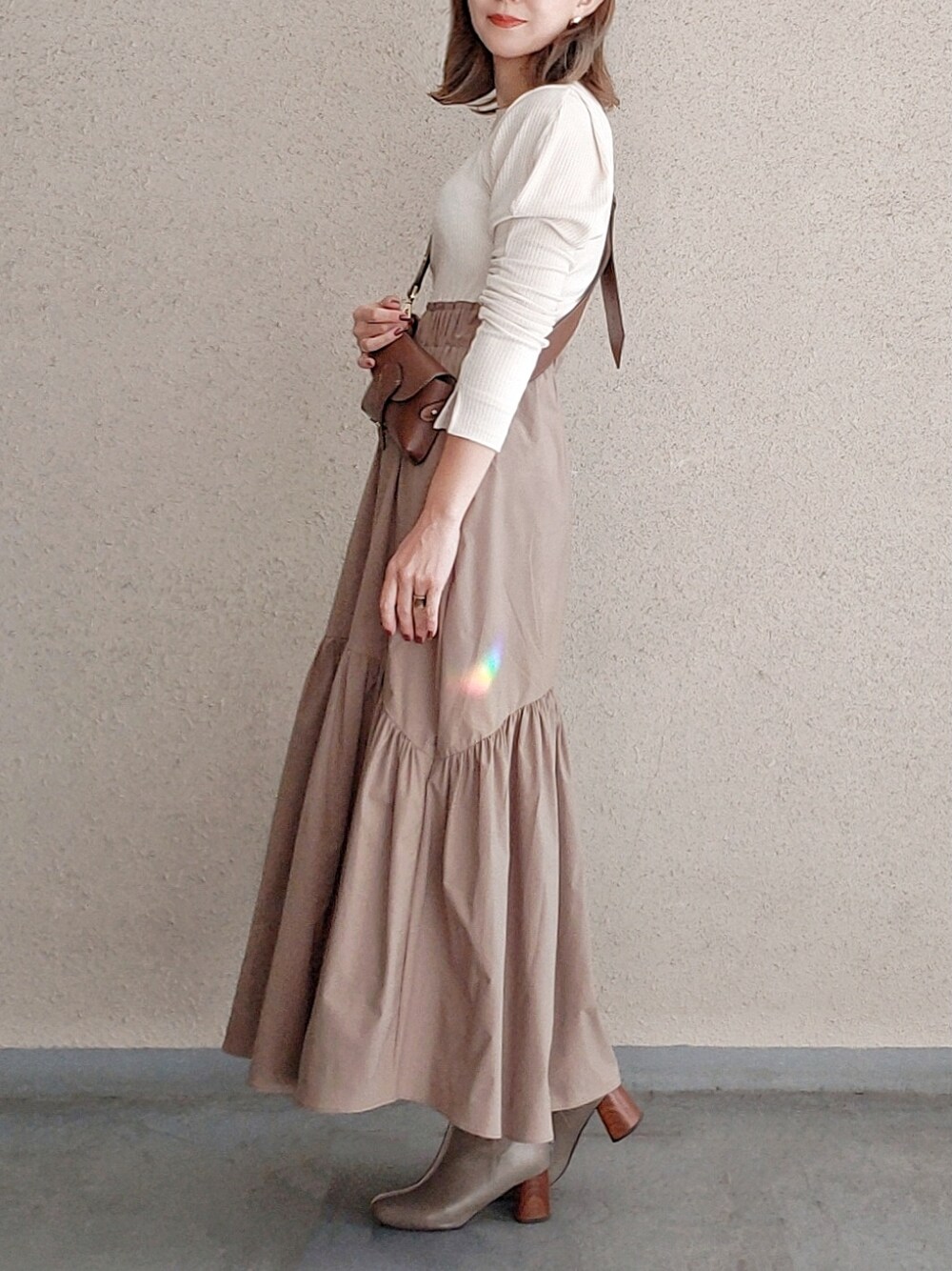 ホワイト系のワンピース、グレー系のブーツ、ブラウン系のショルダーバッグを着用したレディースの冬コーディネートの2枚目の写真