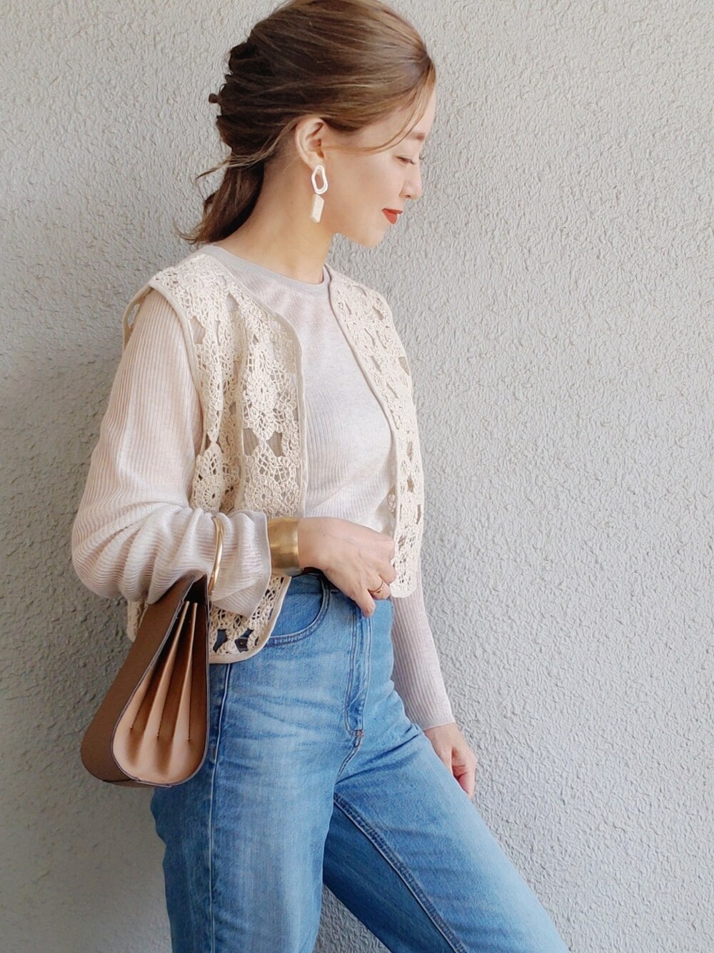 ブラック系のベスト、ベージュ系のニット/セーター、ブルー系のパンツを着用したレディースの春コーディネートの2枚目の写真