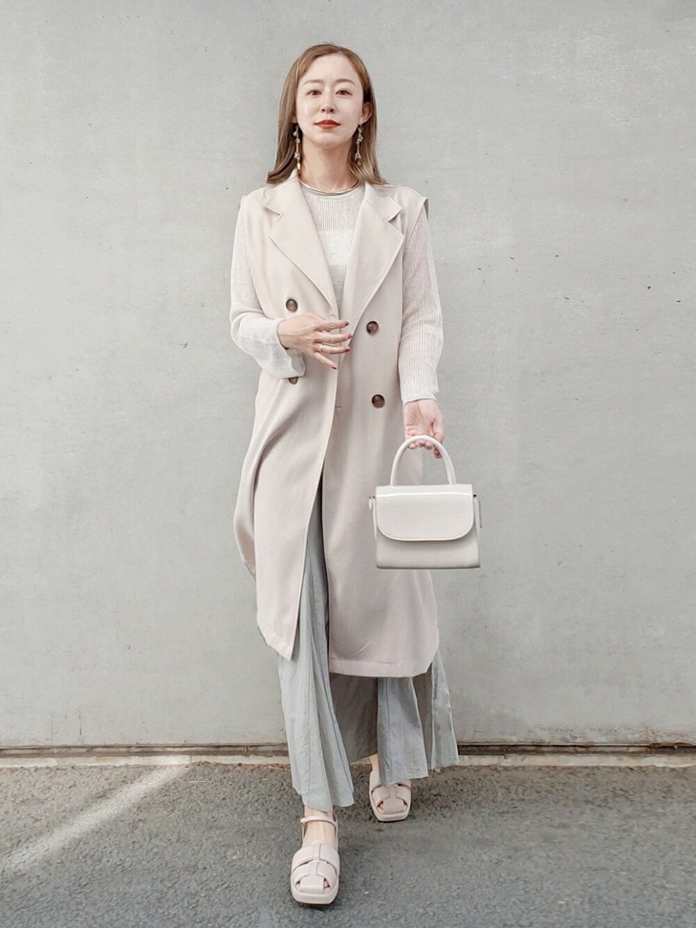 グリーン系のスカート、ベージュ系のニット/セーター、ベージュ系のサンダルを着用したレディースの春コーディネートの2枚目の写真