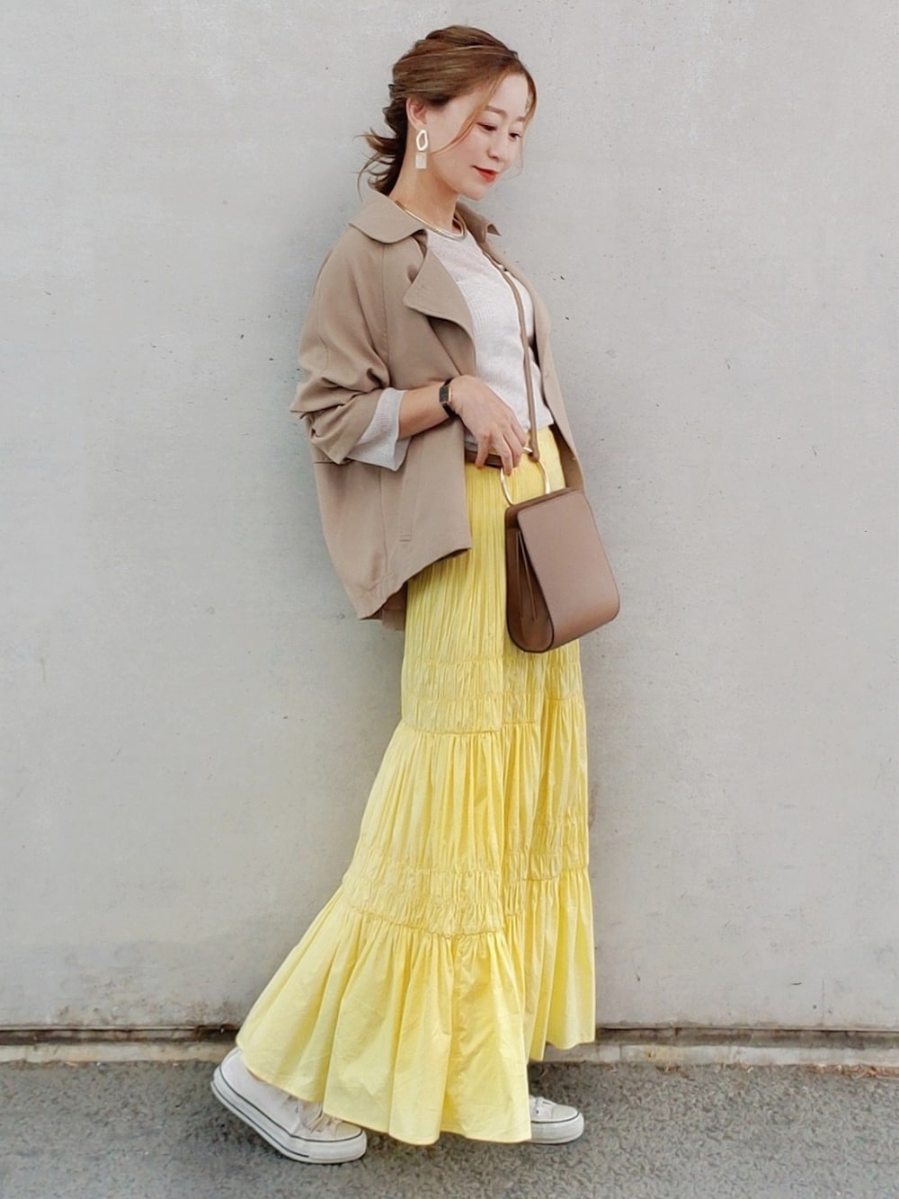 イエロー系のスカート、ベージュ系のニット/セーター、ホワイト系のスニーカーを着用したレディースの春コーディネートの3枚目の写真